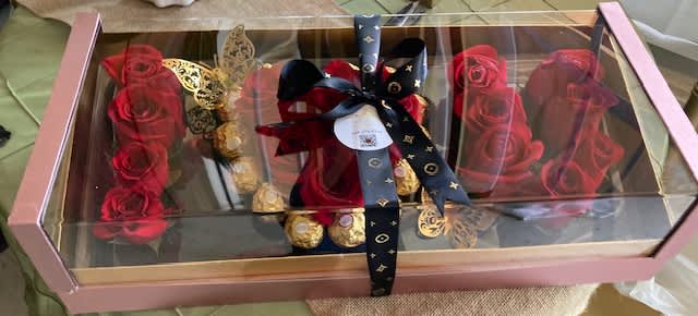 Boxed arrangement of red roses with gold chocolates and a ribbon