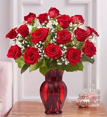 Red roses arranged in a red glass vase with baby's breath