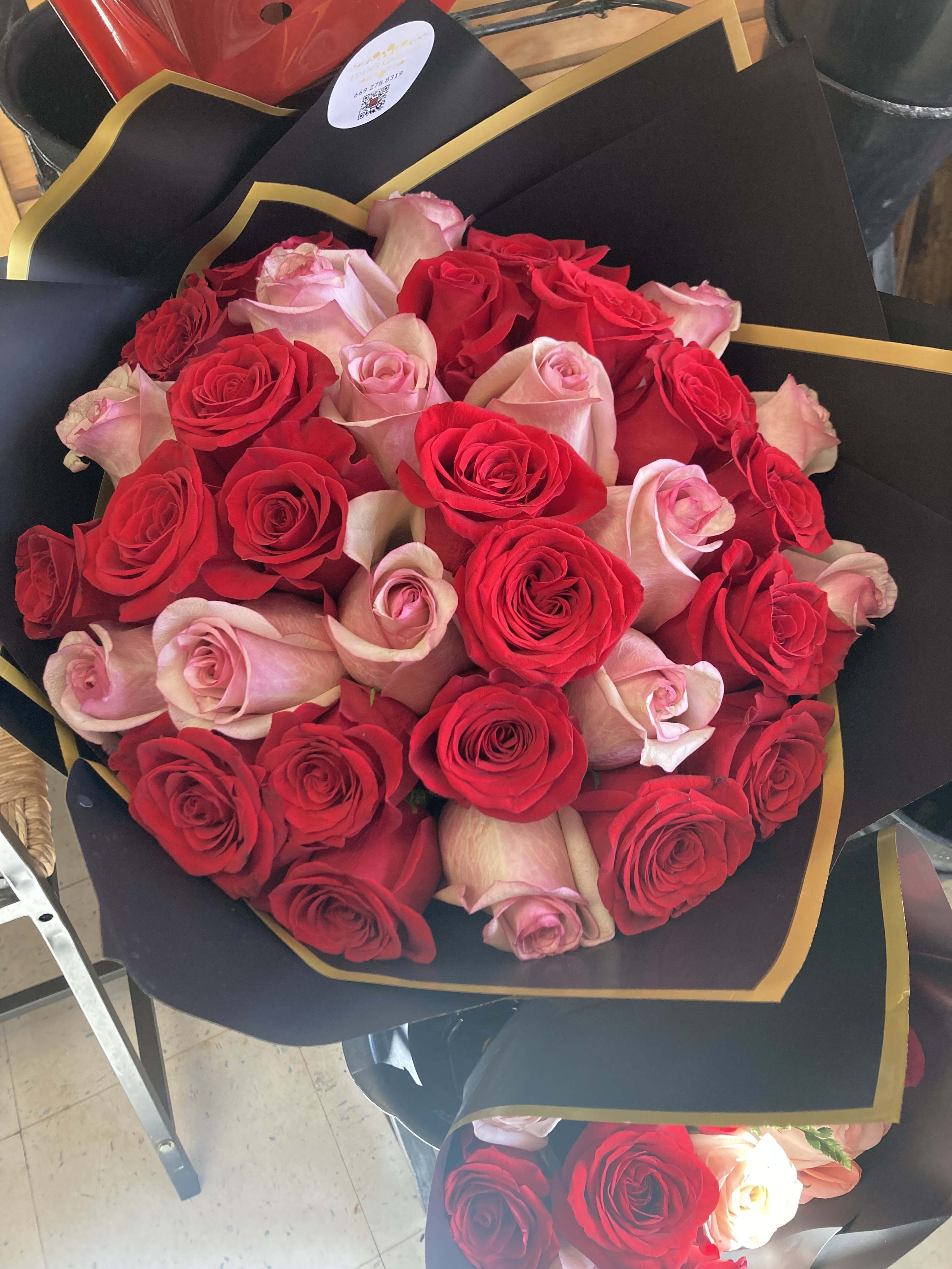 Bouquet of red and pale pink roses wrapped in black paper