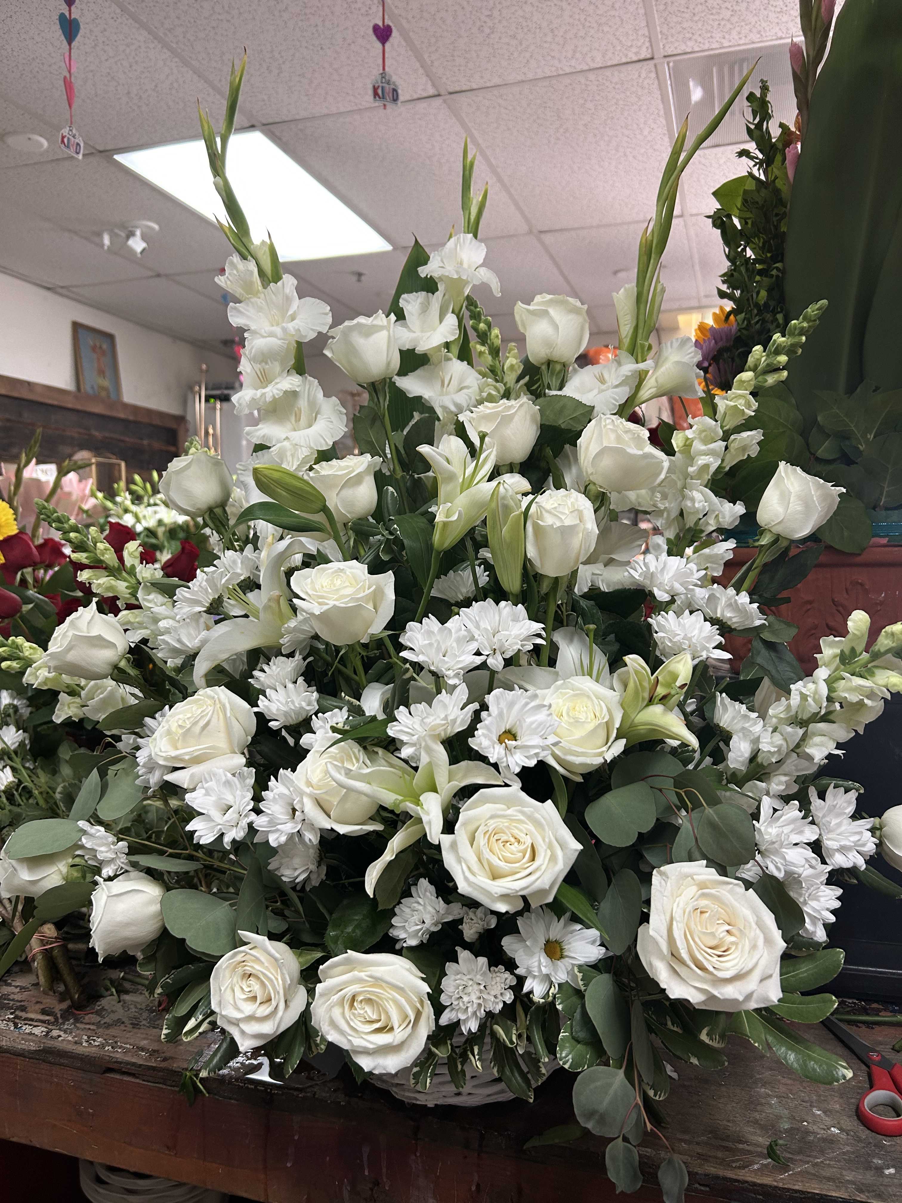 Large white floral arrangement with roses, lilies, and daisies