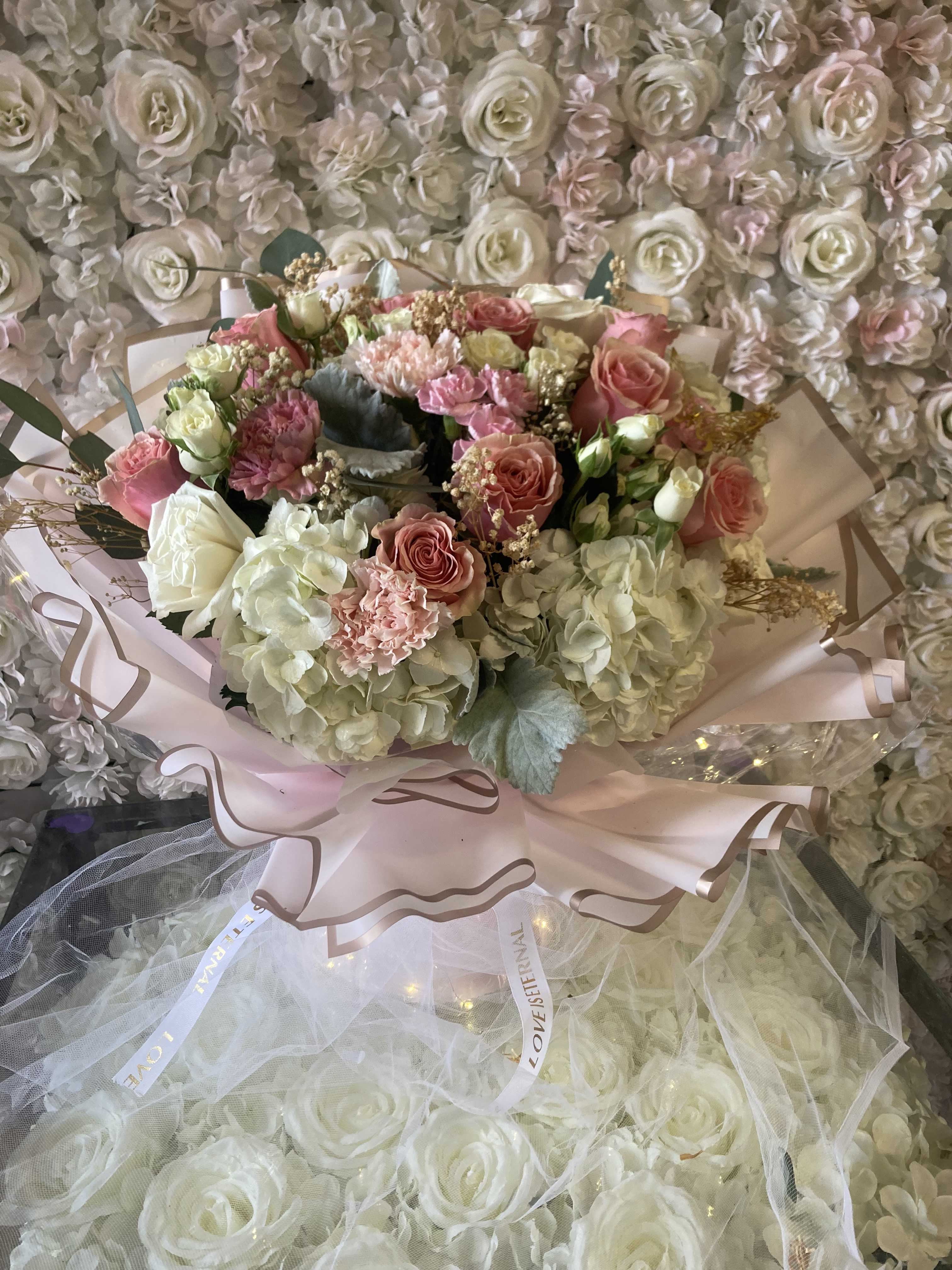 Bouquet of pink and white roses with hydrangeas wrapped in pale pink paper