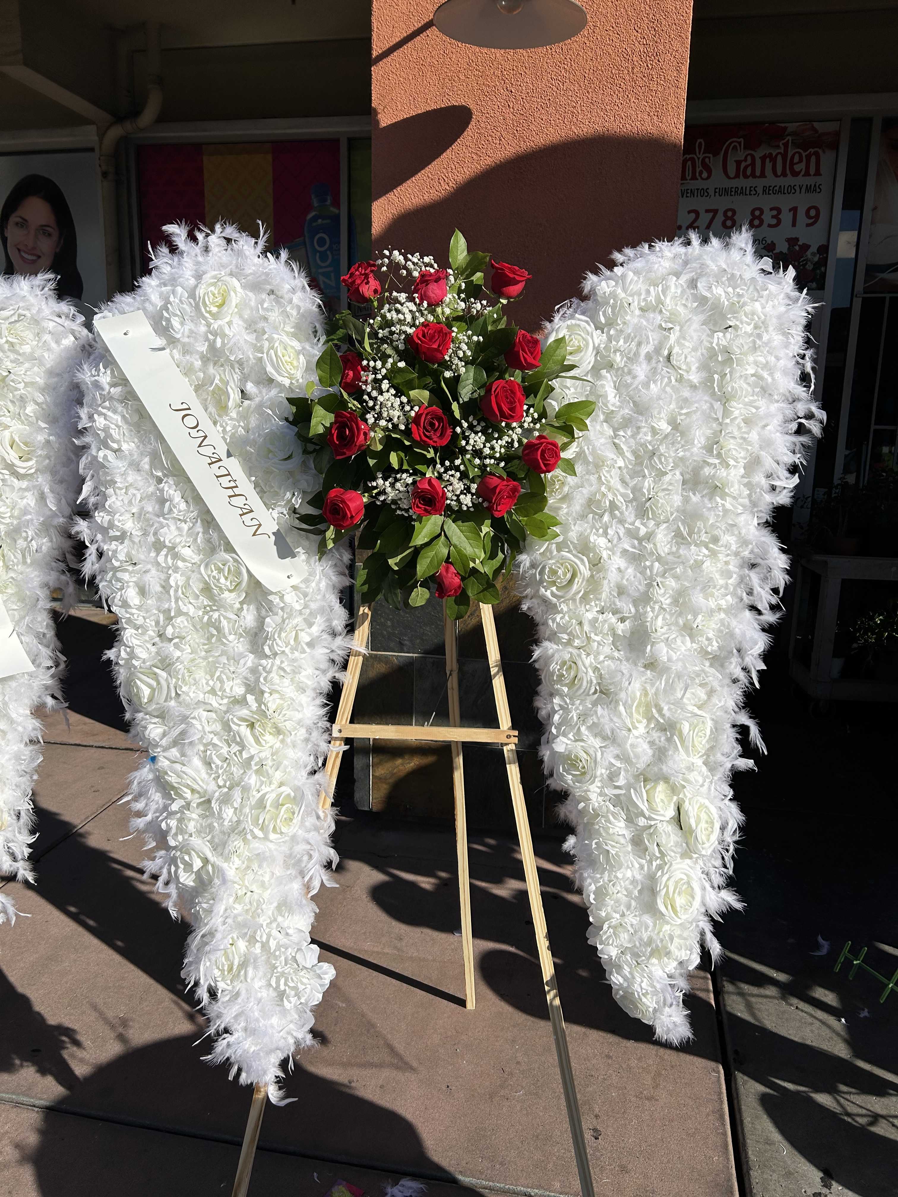 White angel wings floral tribute with red roses on an easel