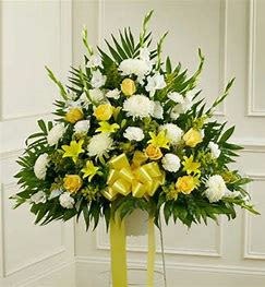 Standing floral spray with white and yellow flowers and a yellow ribbon