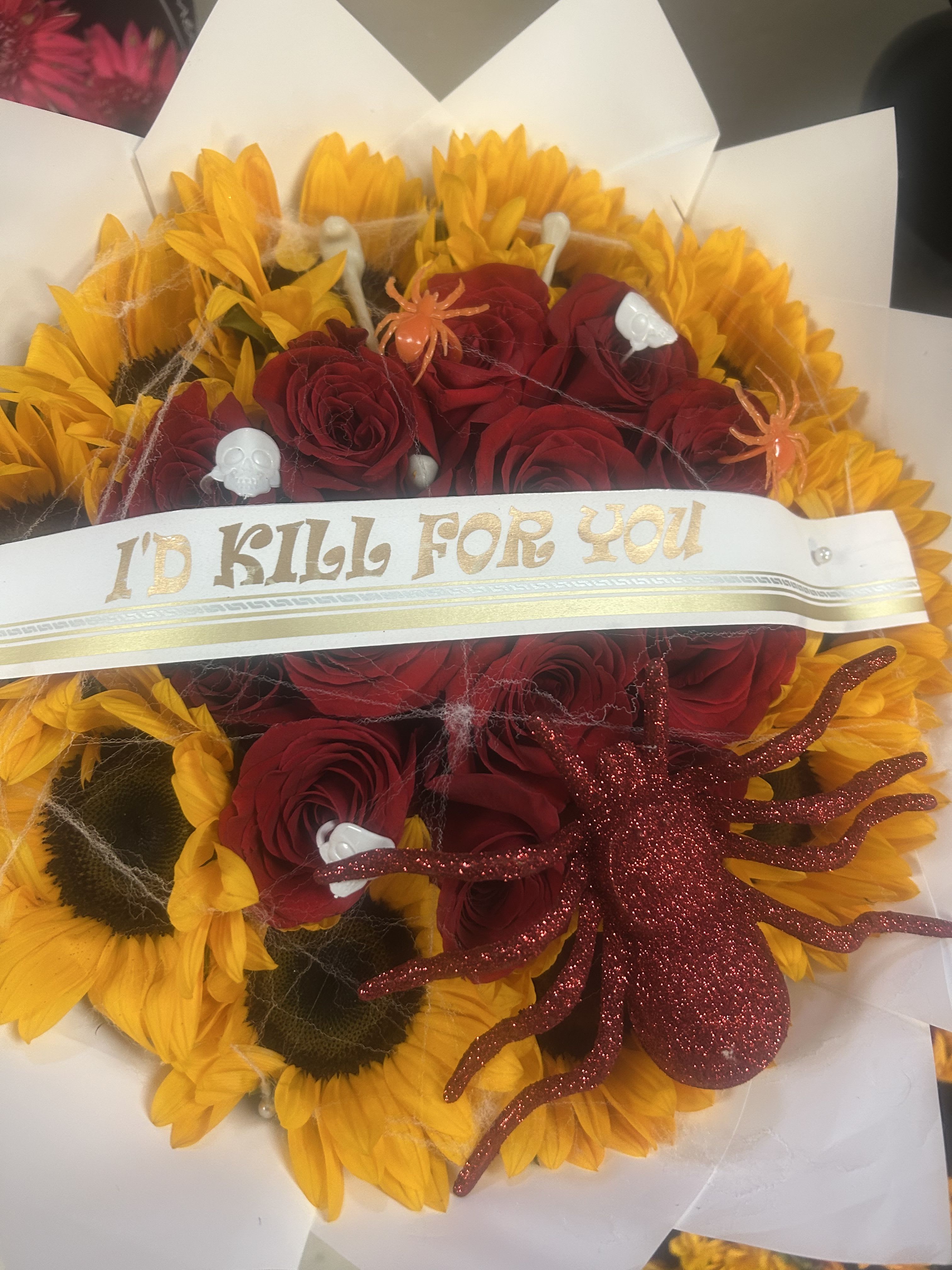 Bouquet of red roses and yellow sunflowers with Halloween decorations