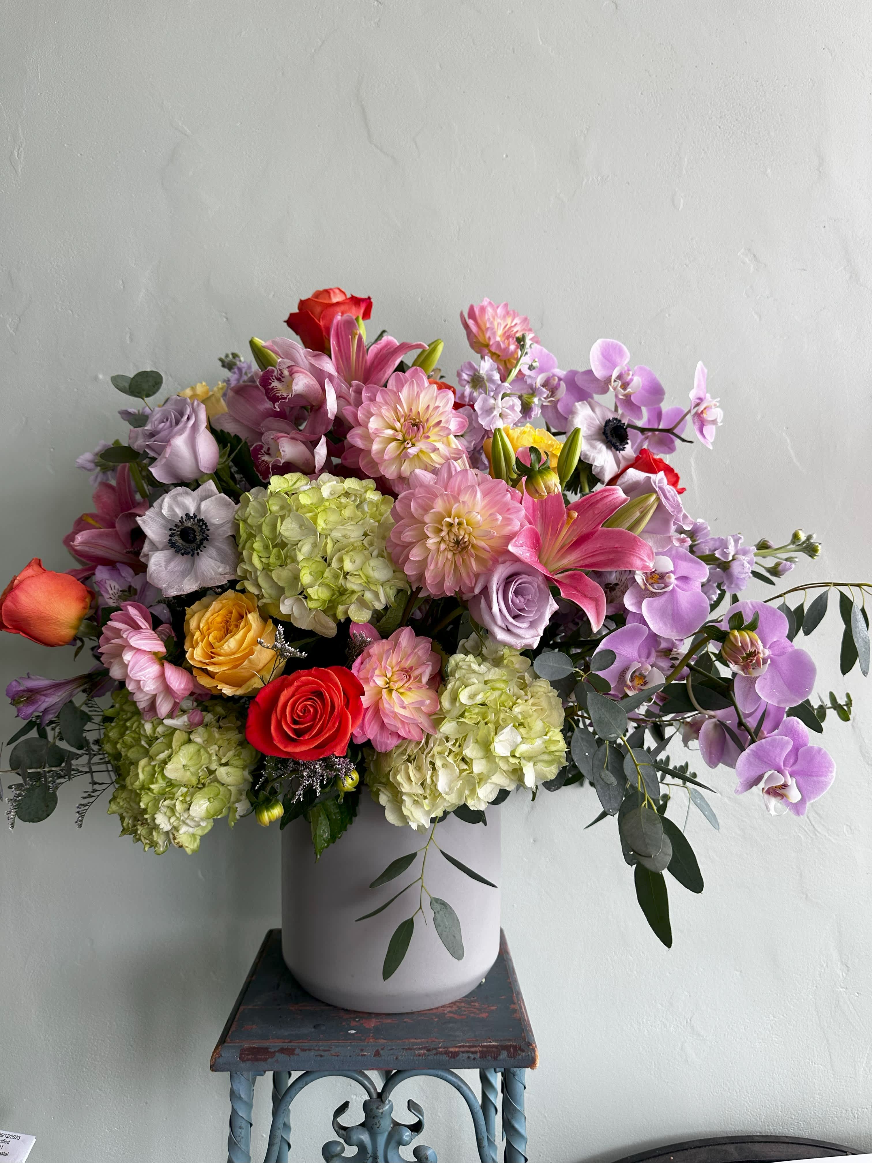 Wildest Dreams - A beautiful and vibrant floral arrangement featuring dahlias, anemones, roses, lilies, and orchids.