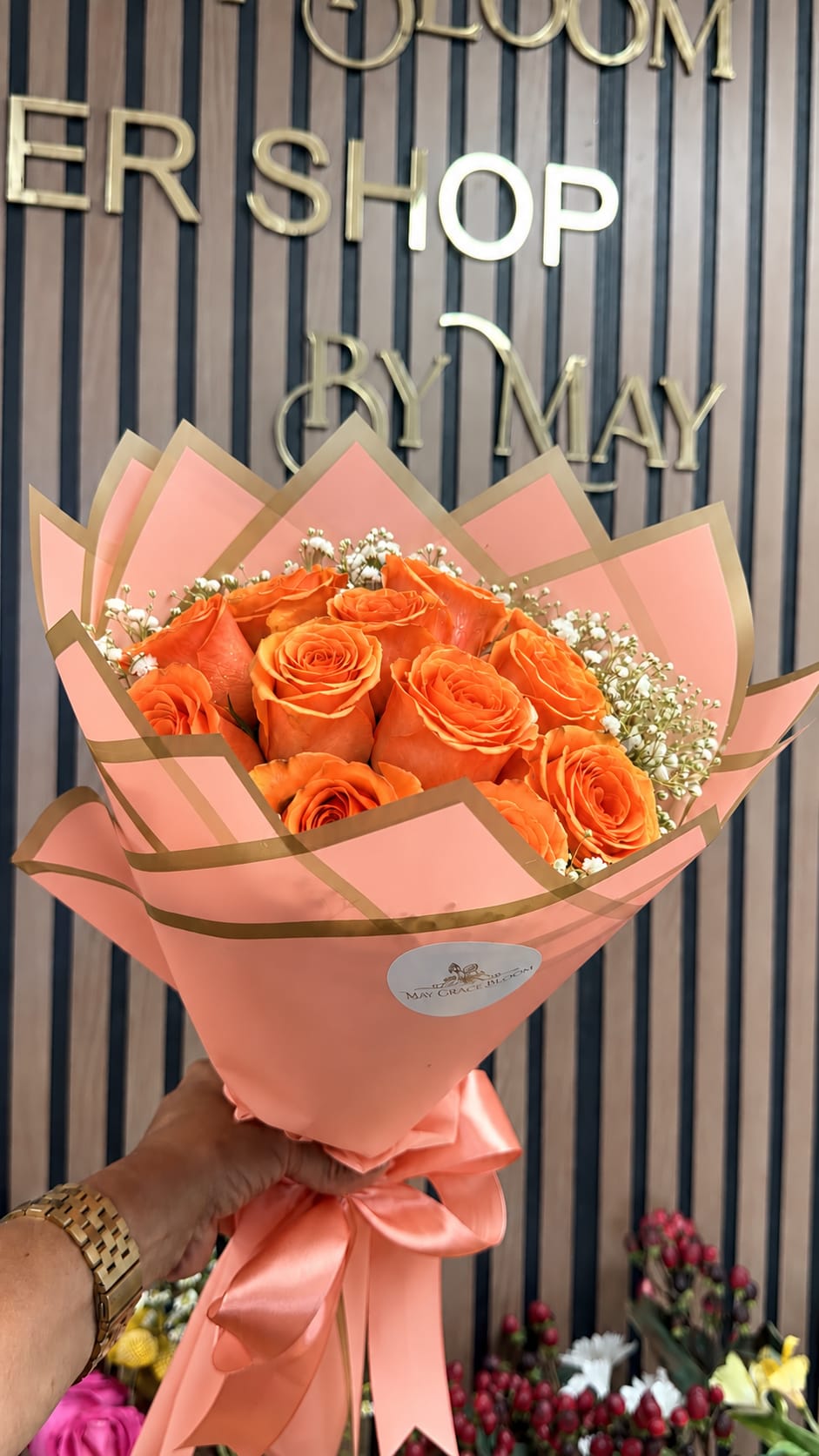 Orange roses wrapped in pink paper with a satin ribbon