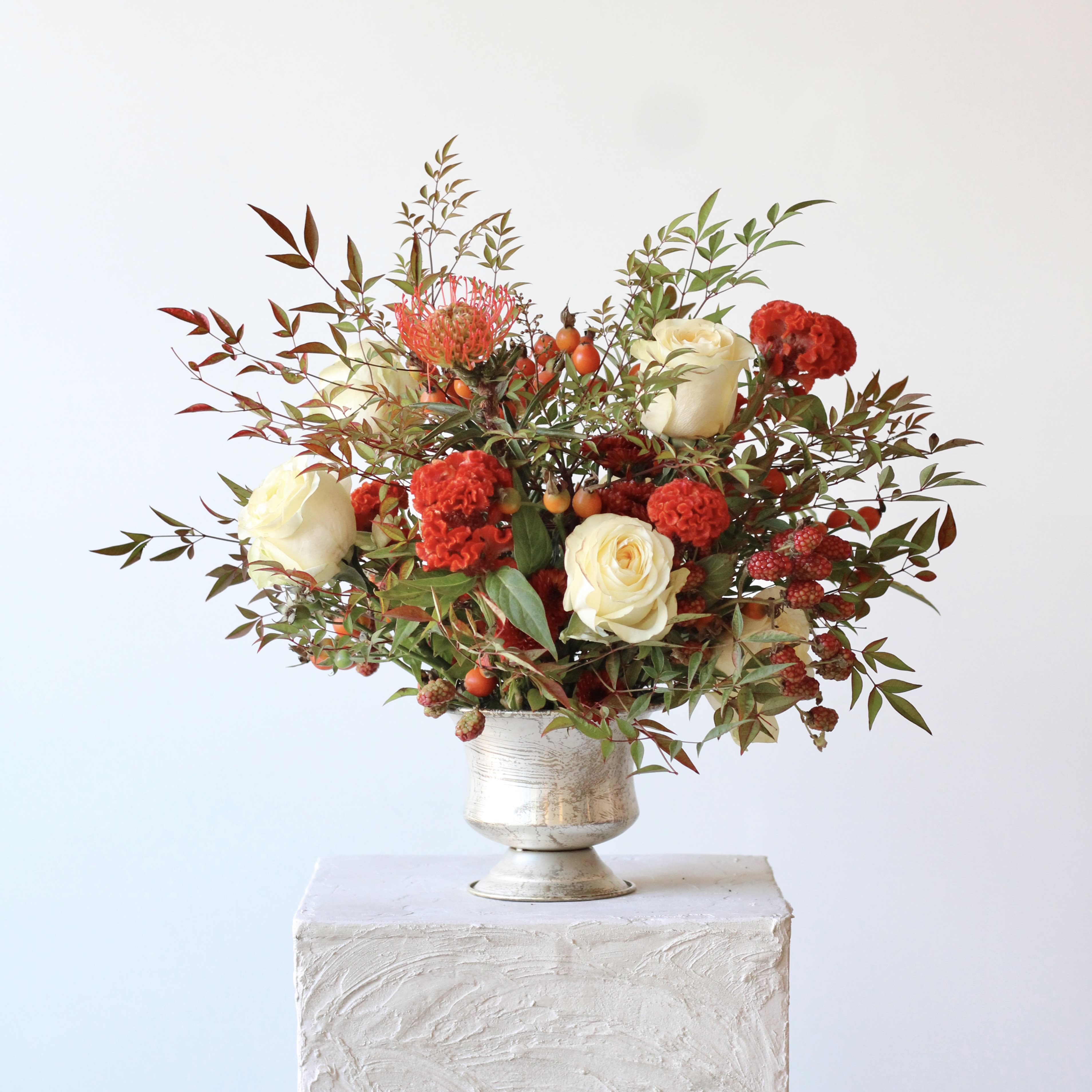 White and red floral arrangement in a silver vase