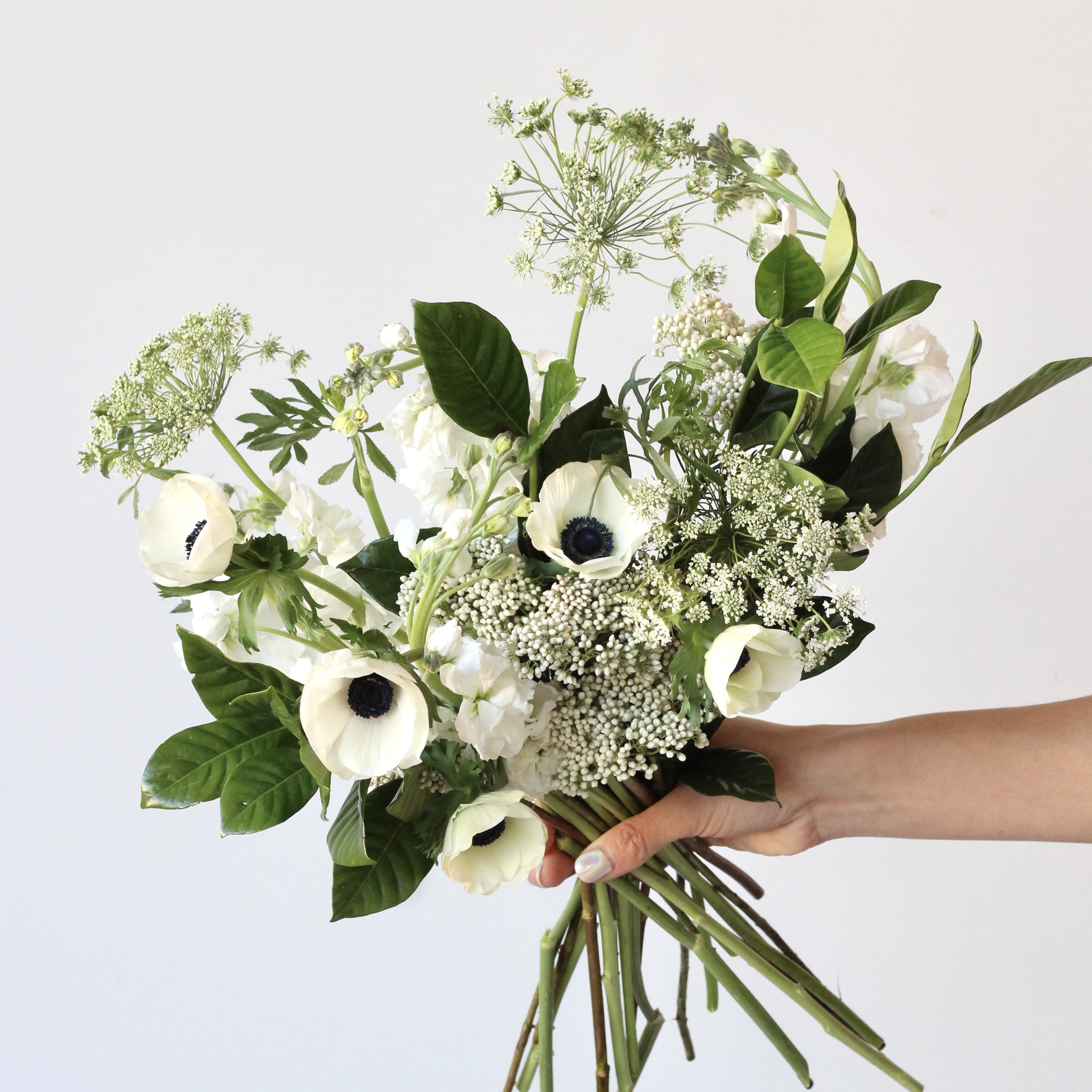 Handheld bouquet of white anemones and airy greenery