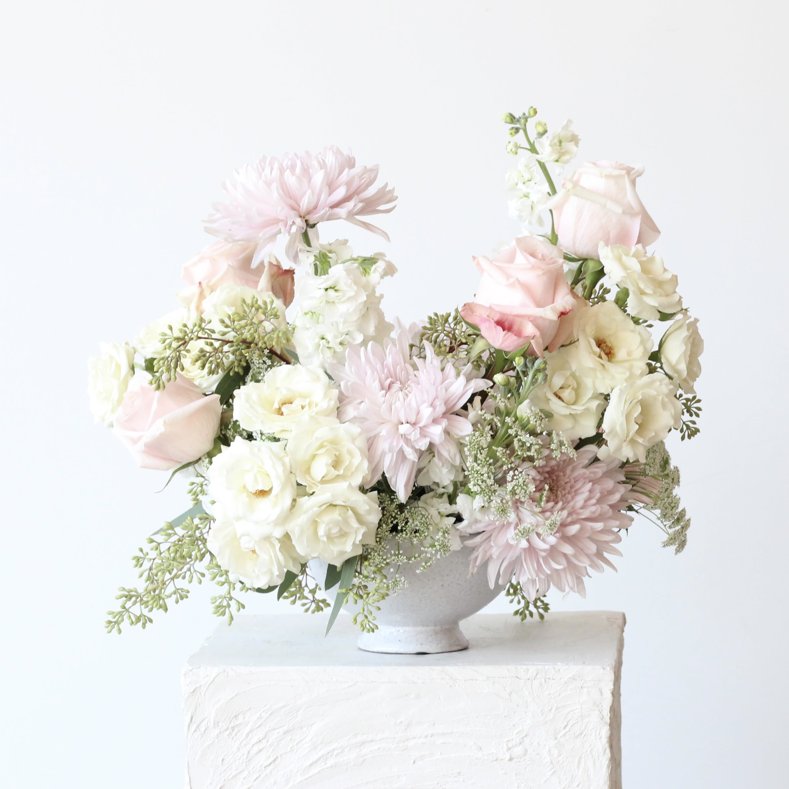 Blush and white floral arrangement in a white vase