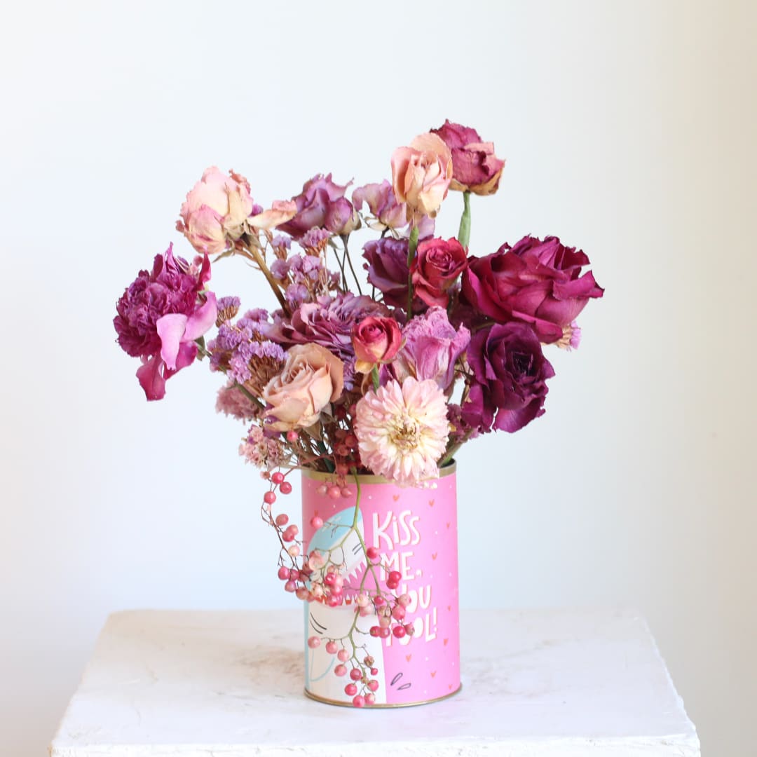 Pink and purple roses in a decorated tin can vase