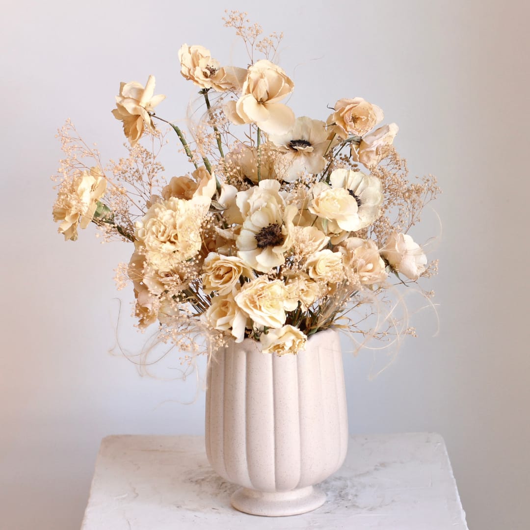 Cream floral arrangement in a ribbed white vase
