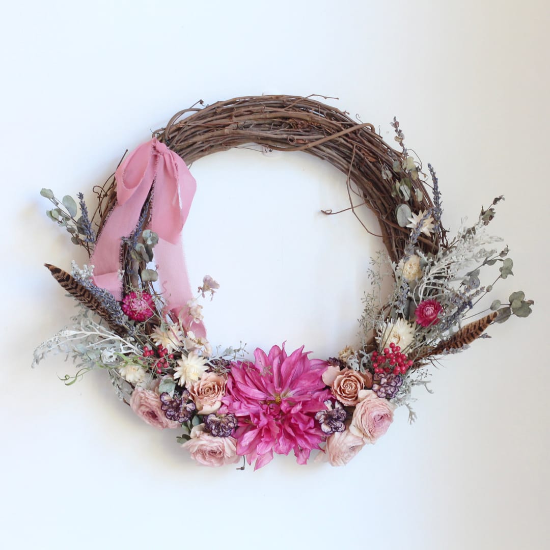 Floral wreath with pink ribbon and mixed pink flowers on a twig base