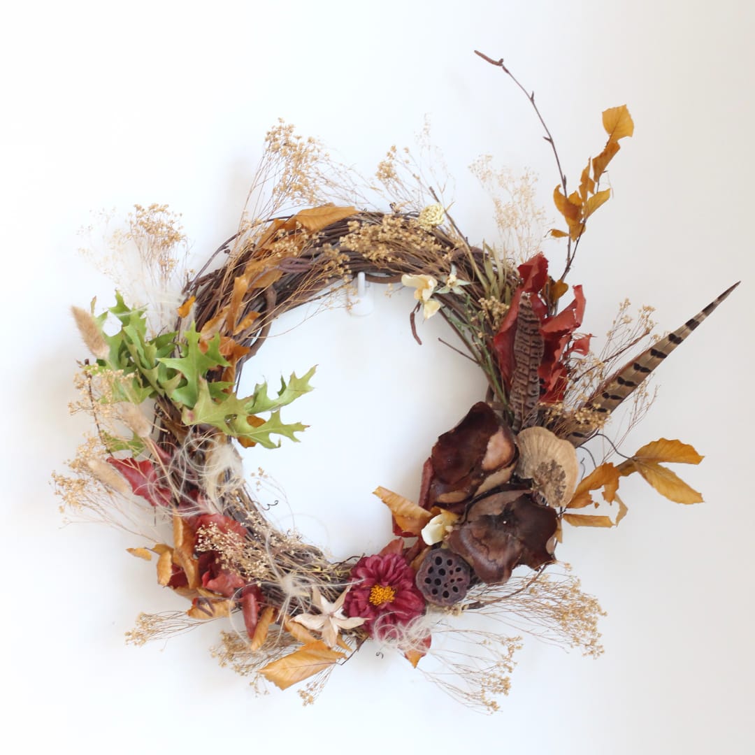 Autumn wreath with dried flowers, leaves, and seed pods on a white background