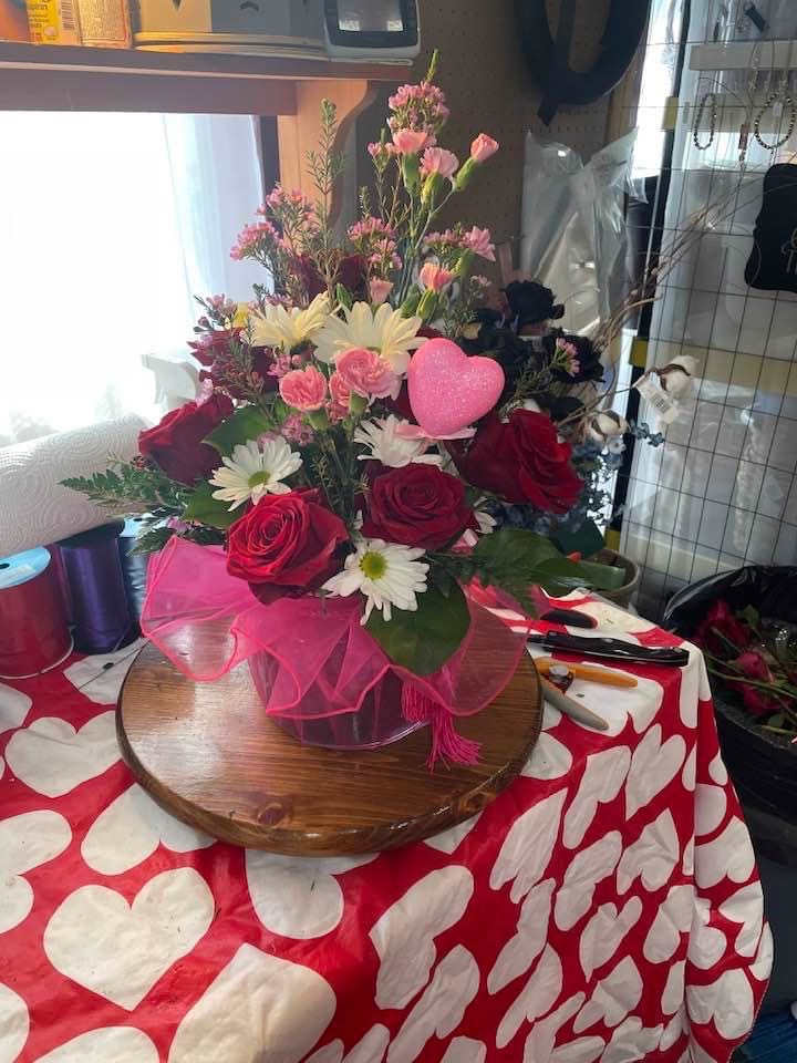 Bouquet of red roses, pink carnations, and white daisies with a pink heart pick