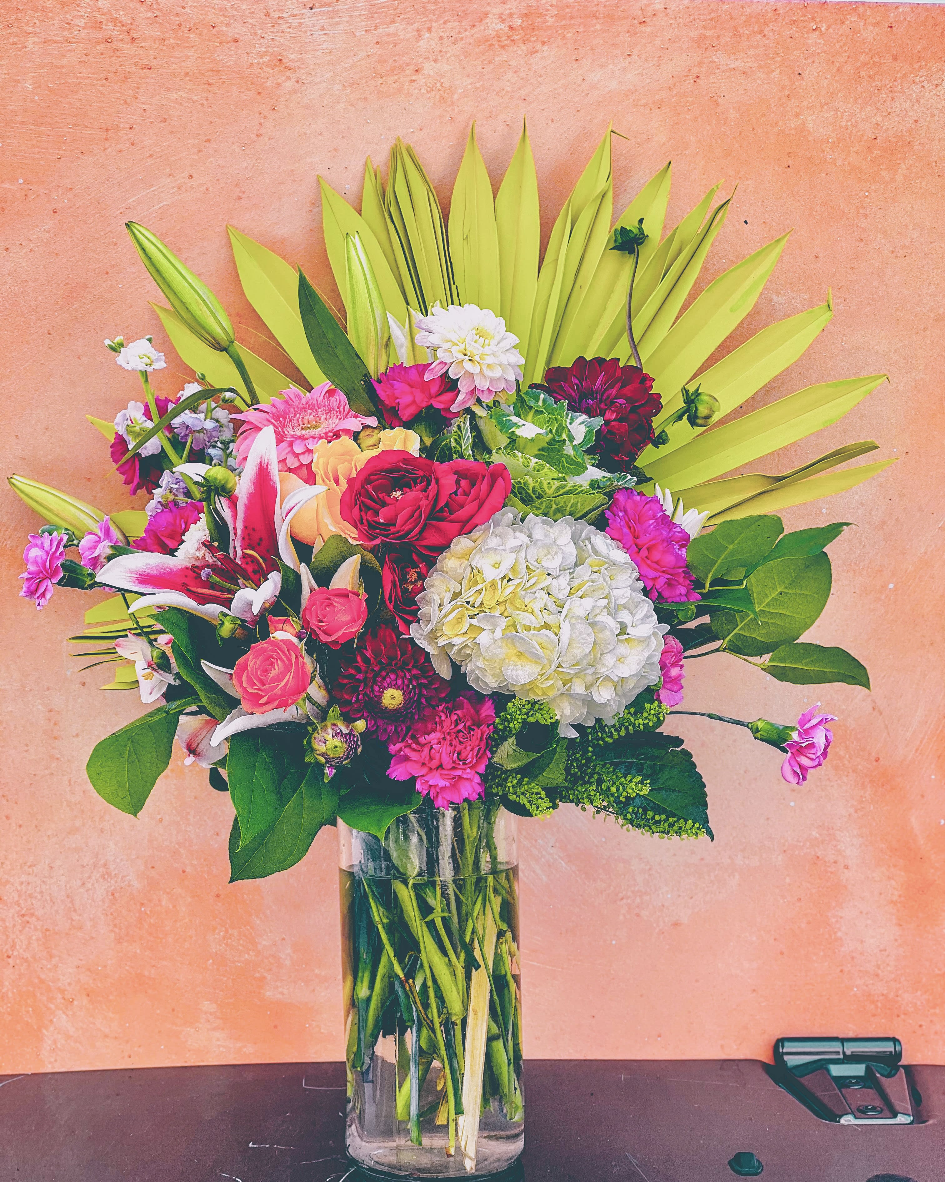 Mixed bouquet of pink, white, and red flowers in a clear glass vase