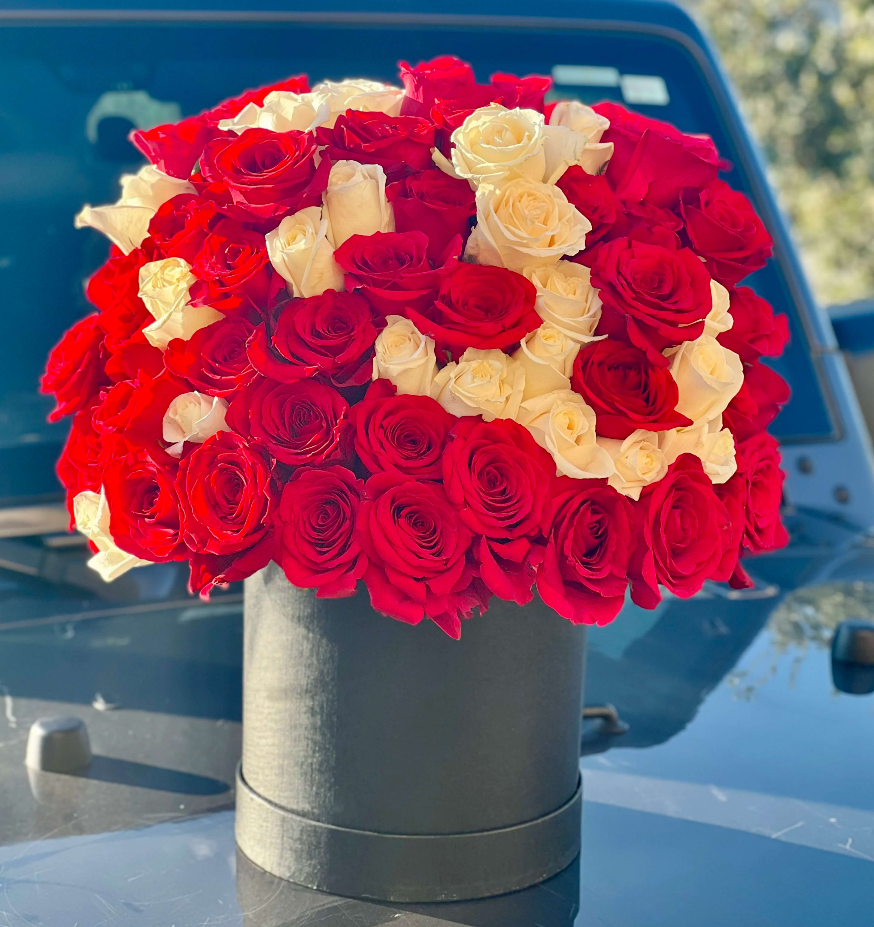 Round bouquet of red and white roses in a black box