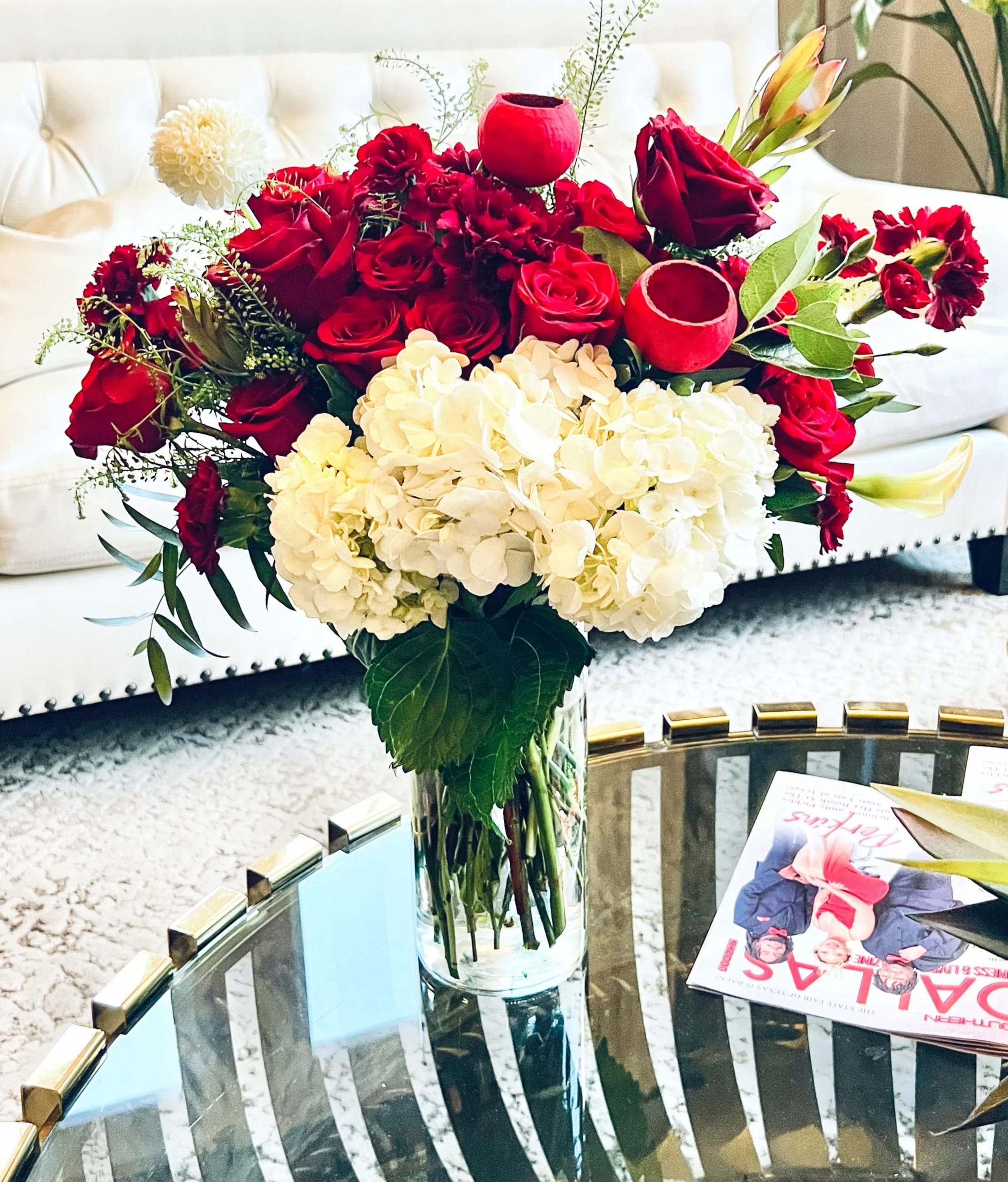 Red roses and white hydrangeas arranged in a clear glass vase