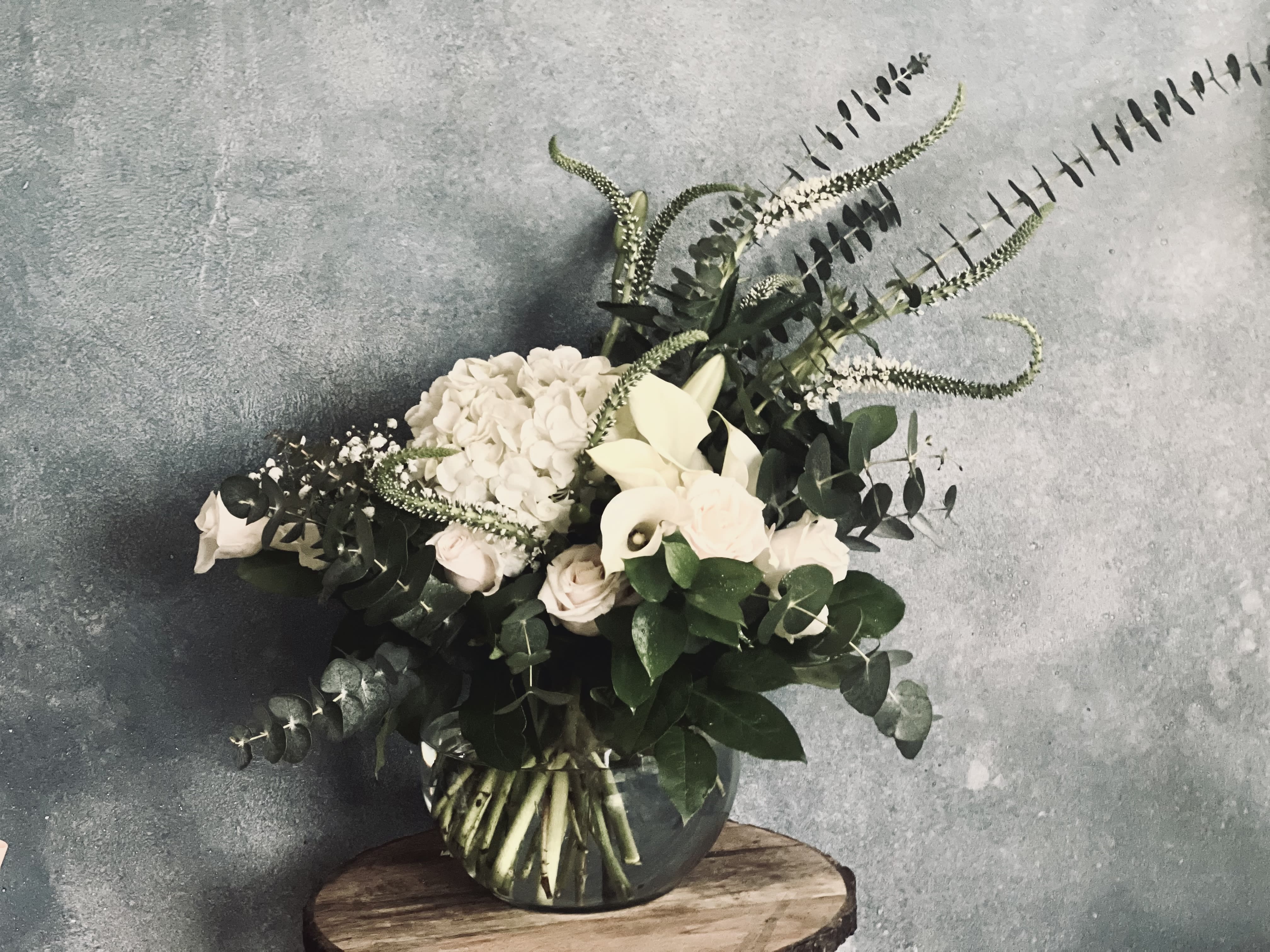 White flowers and greenery arranged in a glass vase