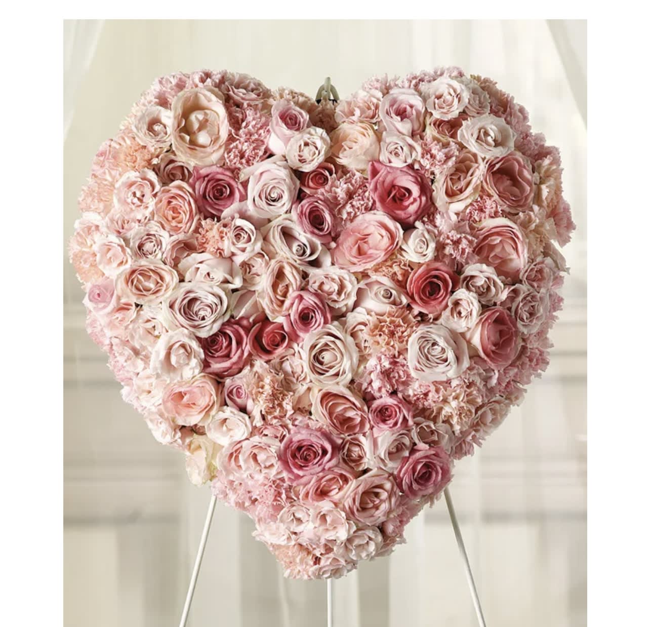 Heart-shaped arrangement of pink and blush roses on a stand