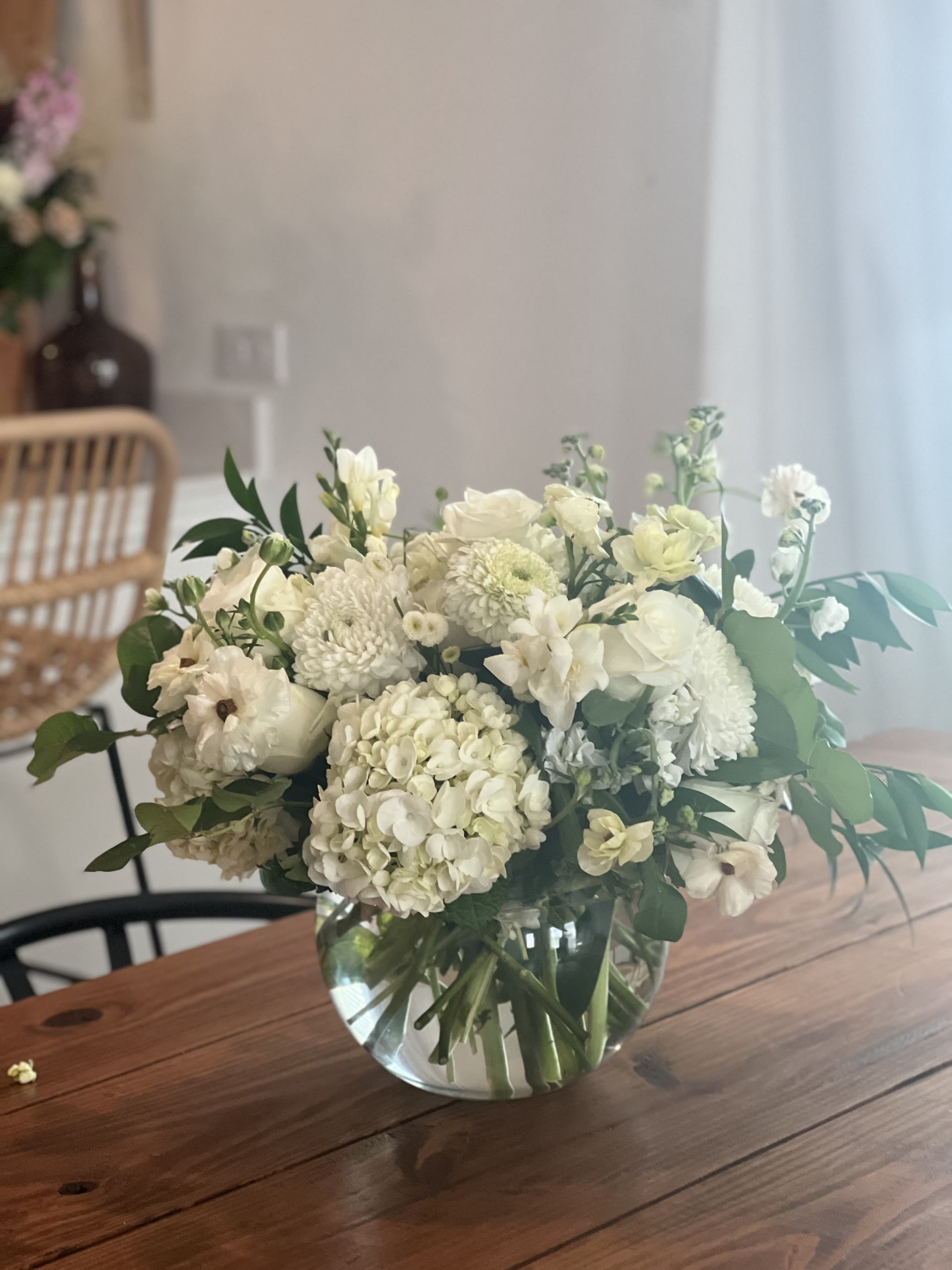 White floral bouquet in a clear glass vase on a wooden table