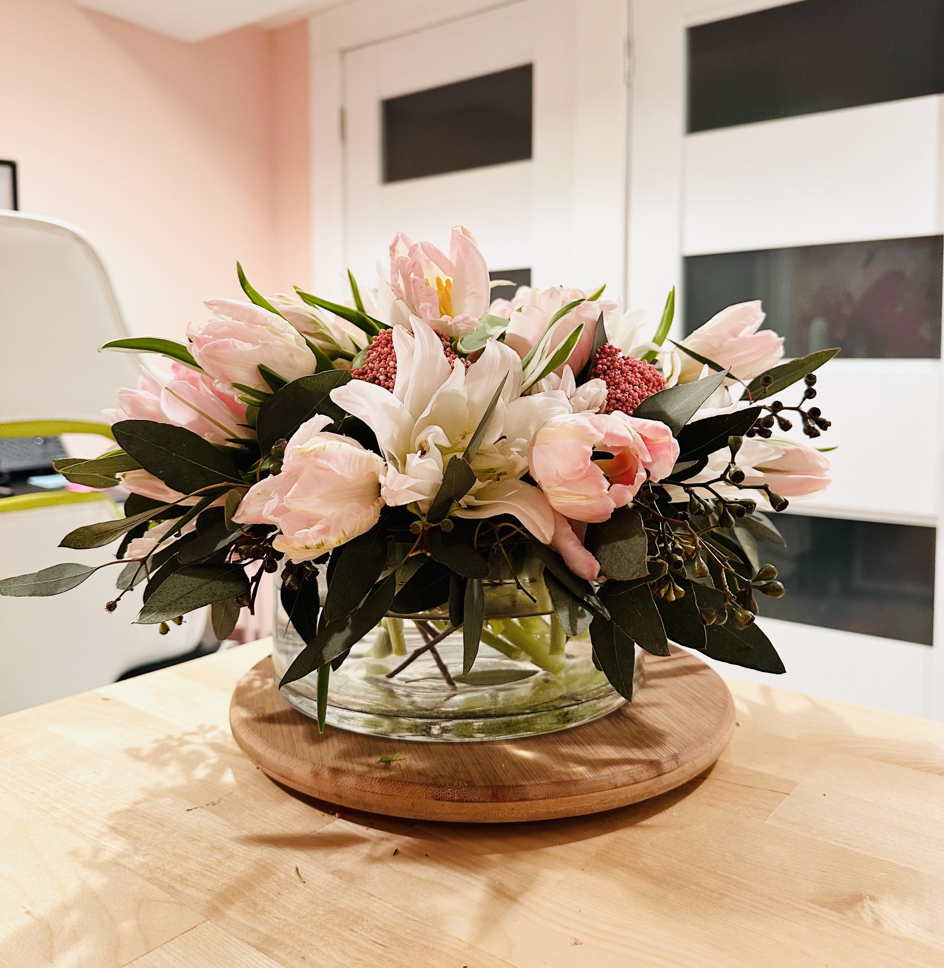 Low floral arrangement of pale pink and white blooms in a glass bowl