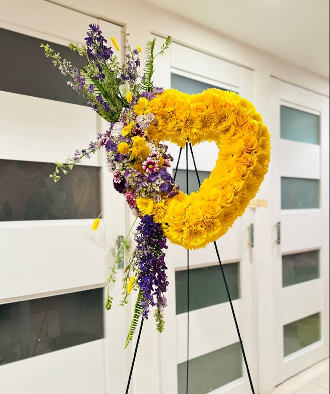 Large yellow floral heart on a black stand with purple flowers cascading down one side