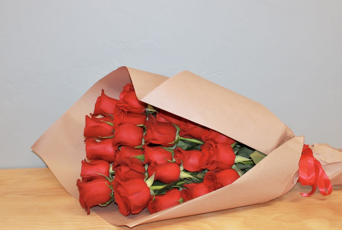 Bouquet of red roses wrapped in tan paper with a red ribbon