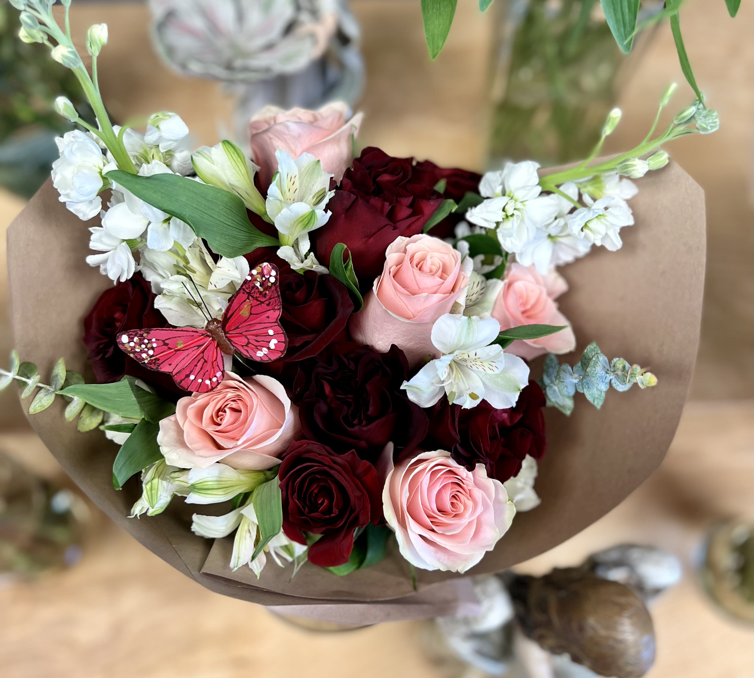 Bouquet of pink and deep red roses with white flowers wrapped in brown paper