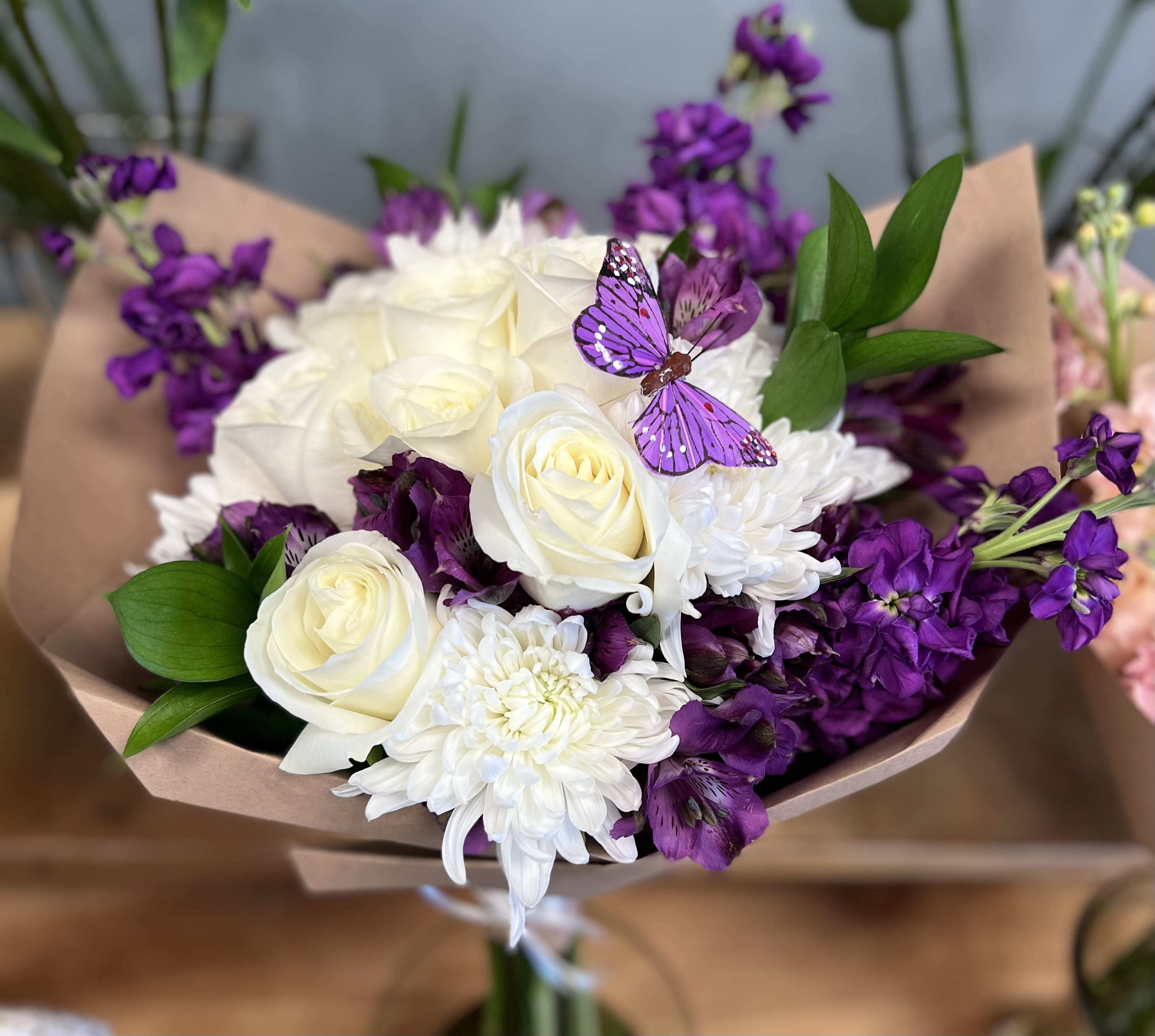 Bouquet of white roses and purple flowers with a butterfly decoration