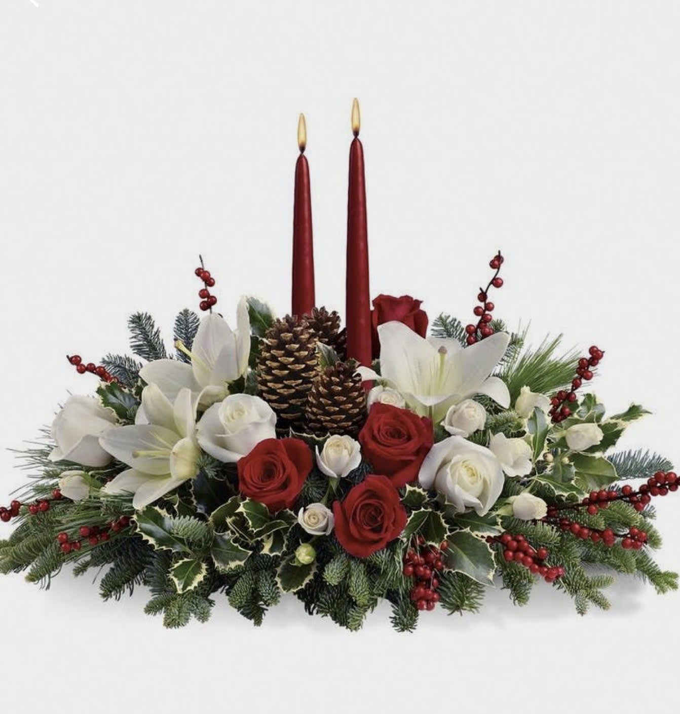 Holiday centerpiece with red candles, white lilies, and red and white roses