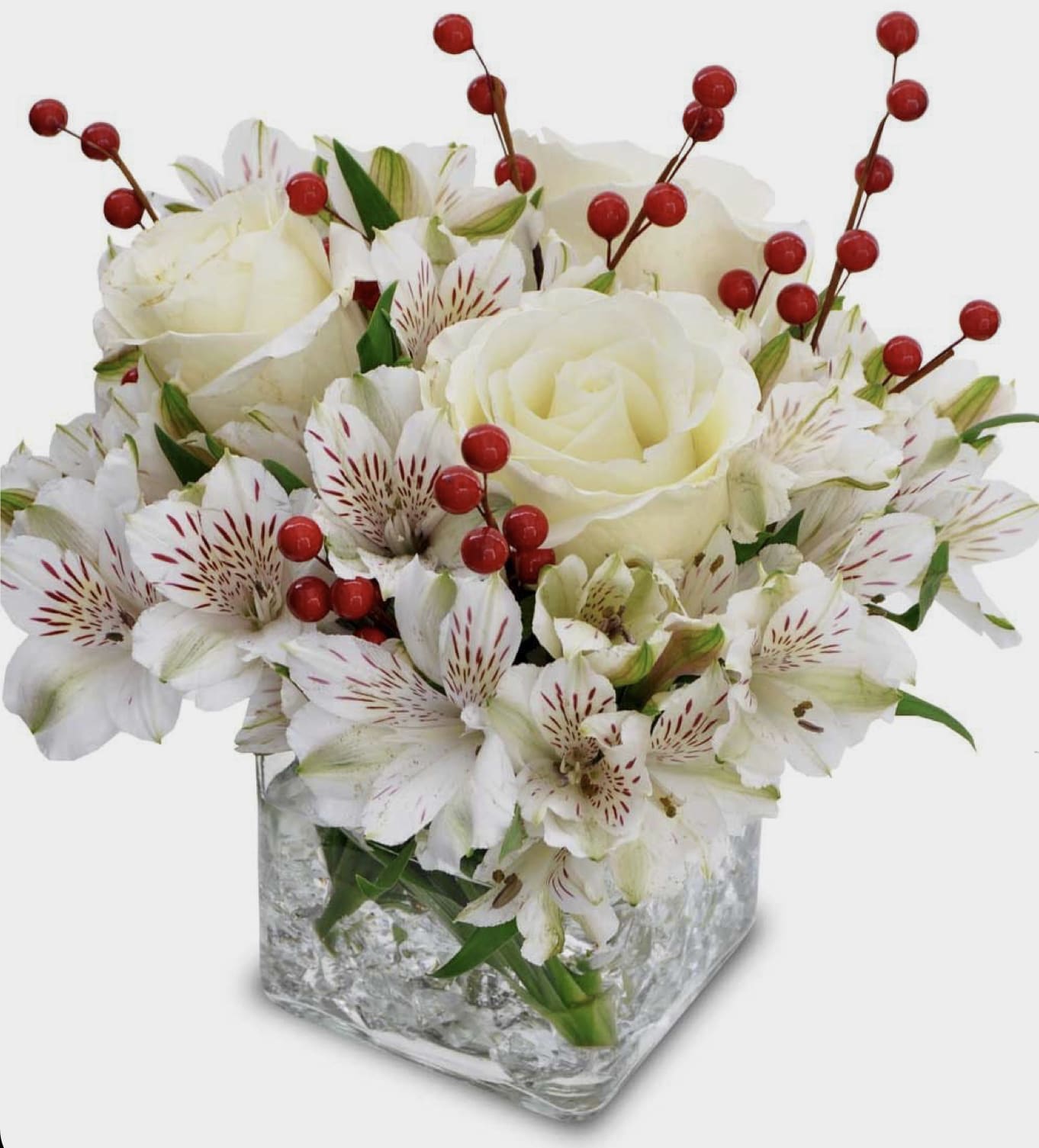 White roses and alstroemeria in a square glass vase with red berry stems