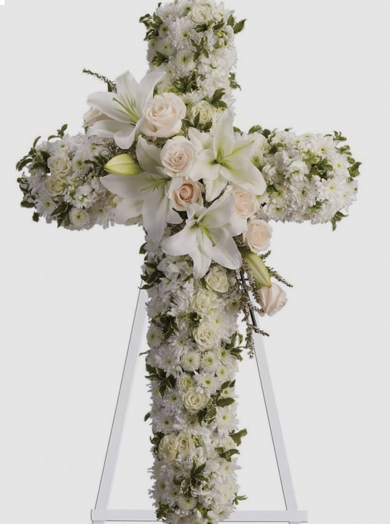 White floral cross arrangement with lilies and roses on an easel