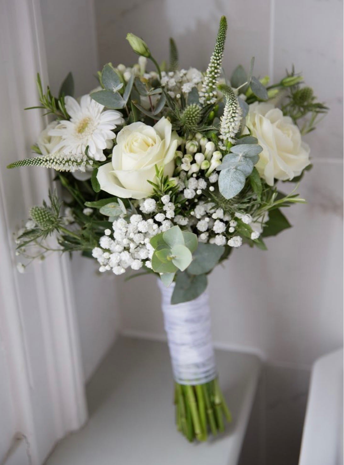White rose bouquet with baby’s breath and eucalyptus wrapped in white ribbon