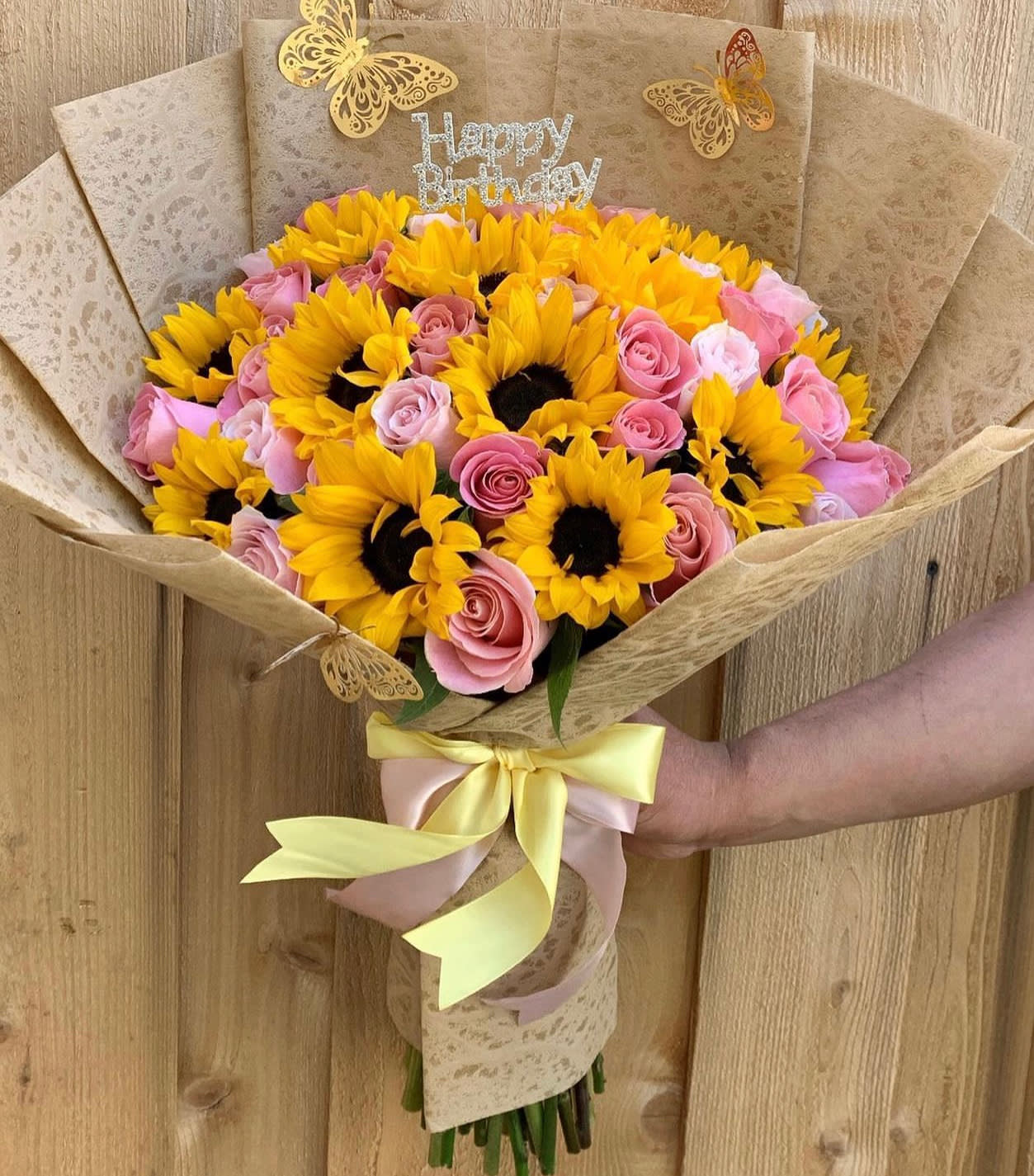 Bouquet of yellow sunflowers and pink roses with a birthday topper