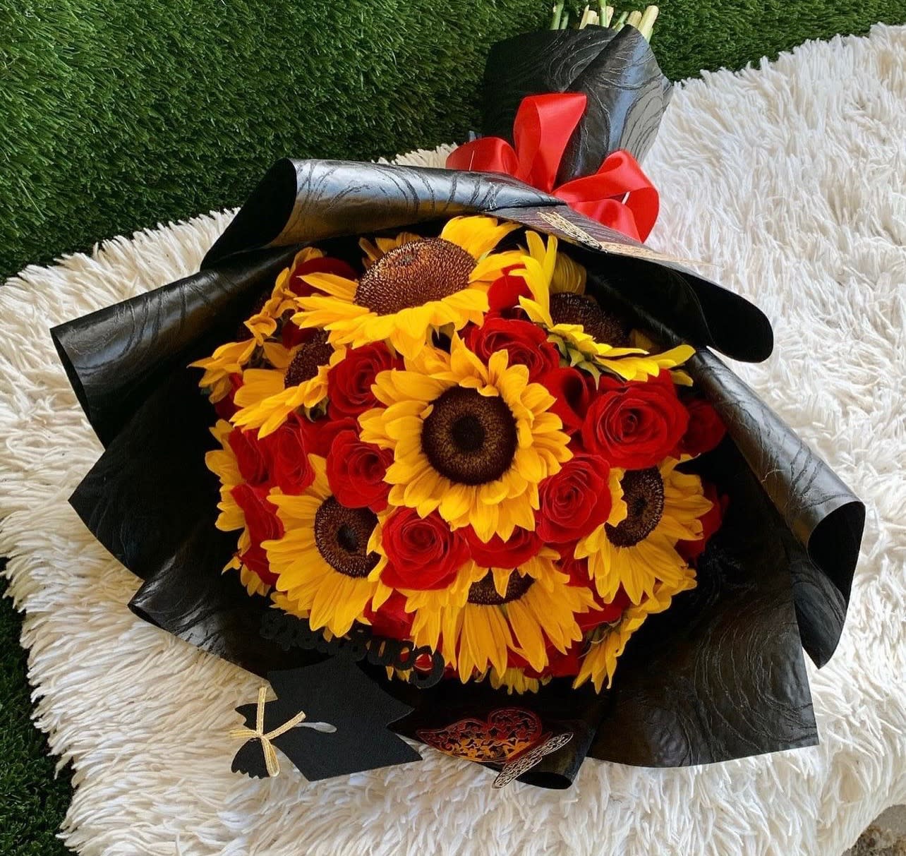 Bouquet of red roses and yellow sunflowers wrapped in black paper