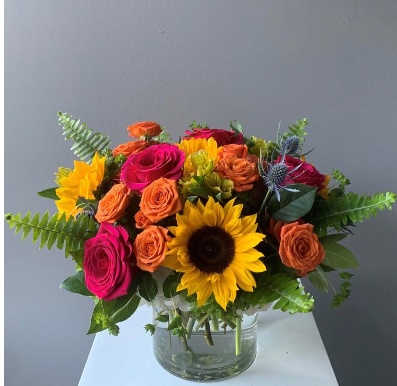 Bouquet of bright roses and sunflowers in a clear glass vase