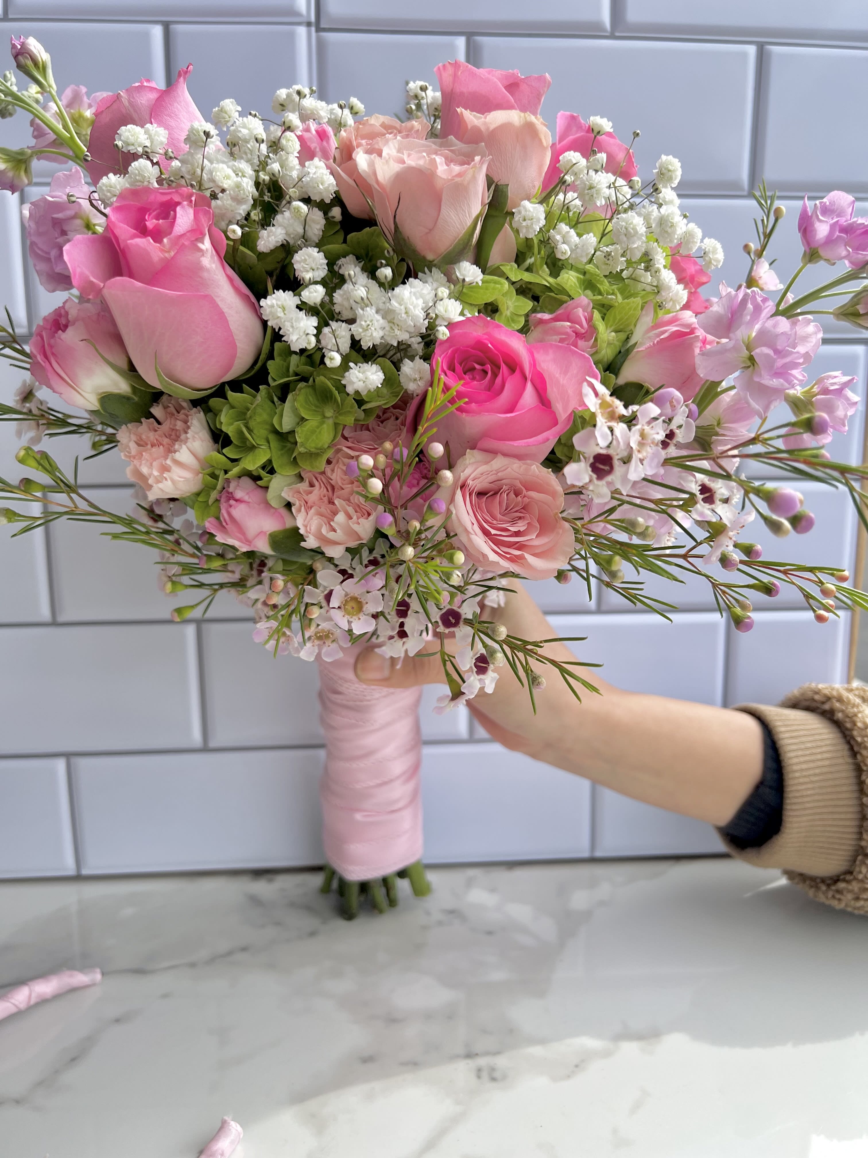 Hand-tied bouquet of pink roses and white baby's breath
