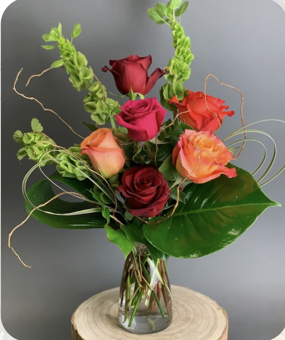 Mixed roses in a clear glass vase with curly greenery