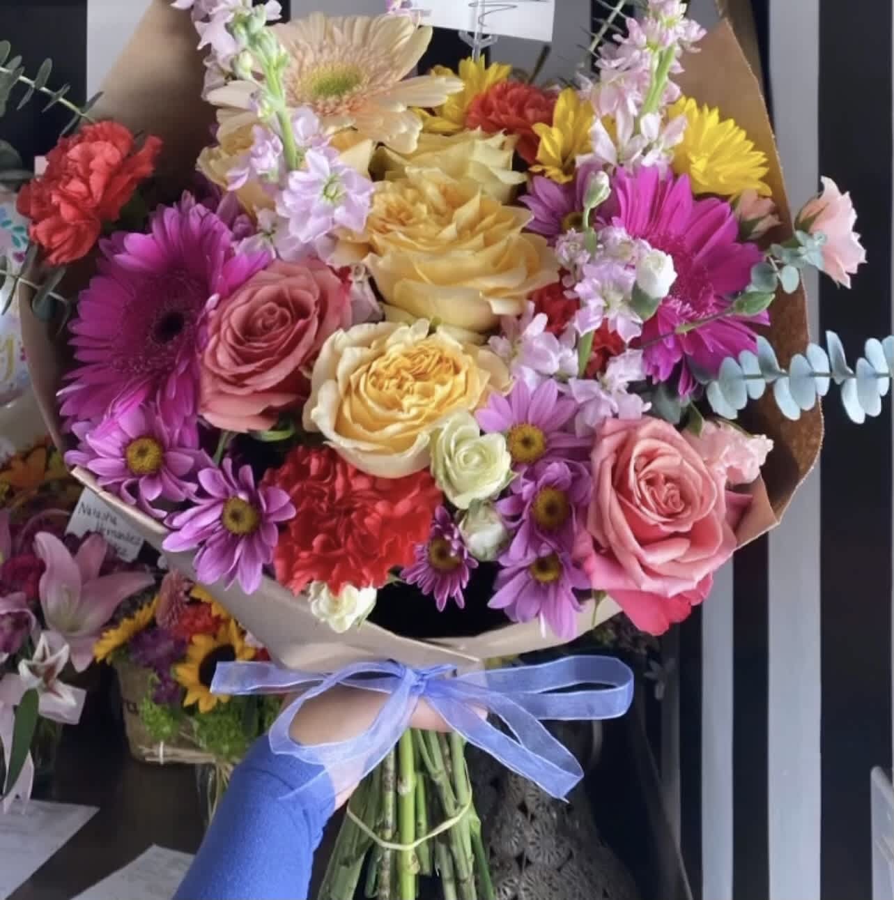 Colorful bouquet of roses and daisies tied with a blue ribbon