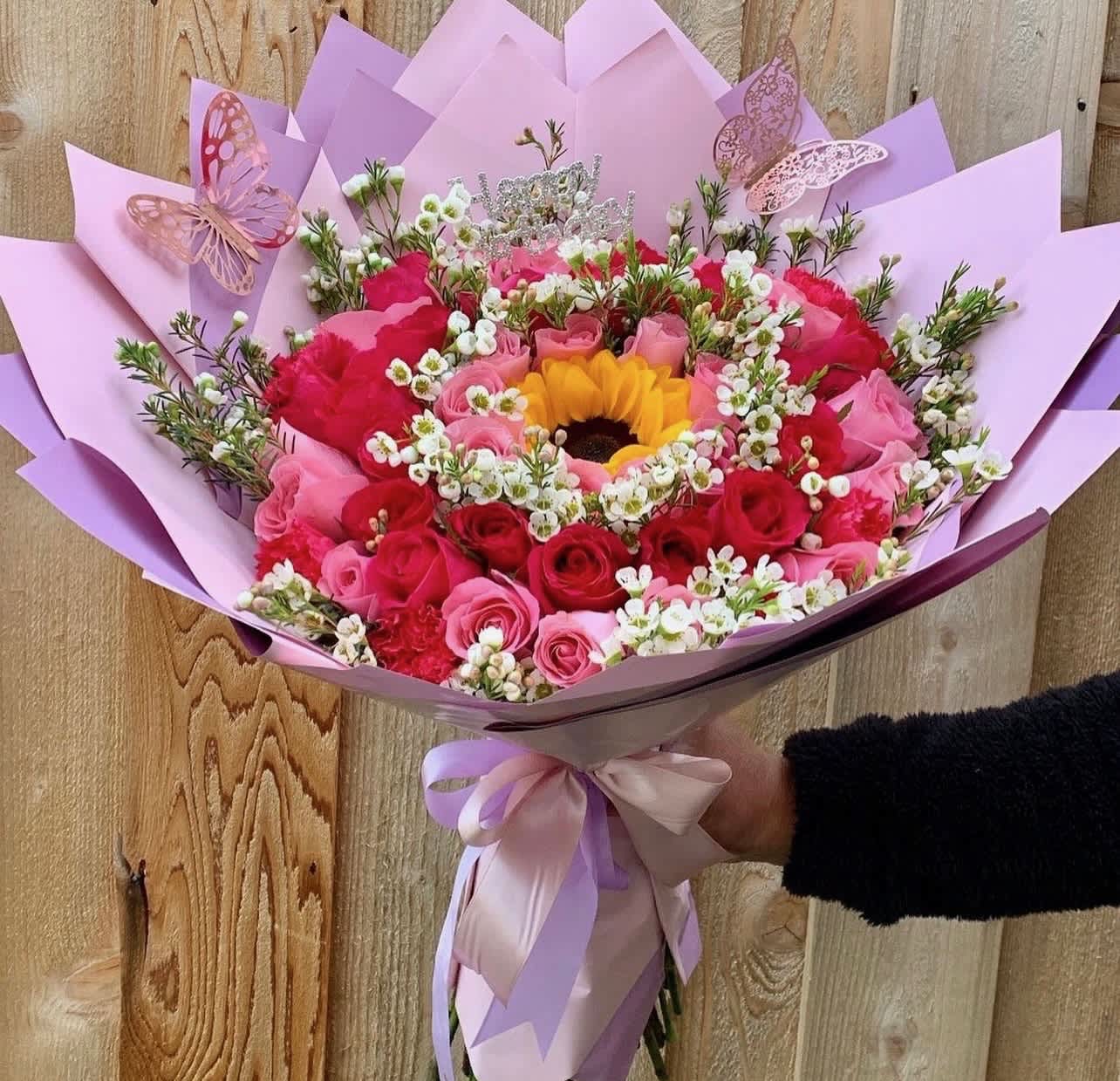Pink and red rose bouquet with a sunflower center and butterfly decorations