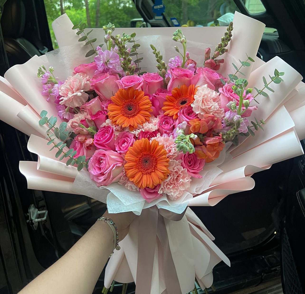 Pink rose bouquet with orange gerbera daisies and pale wrapping