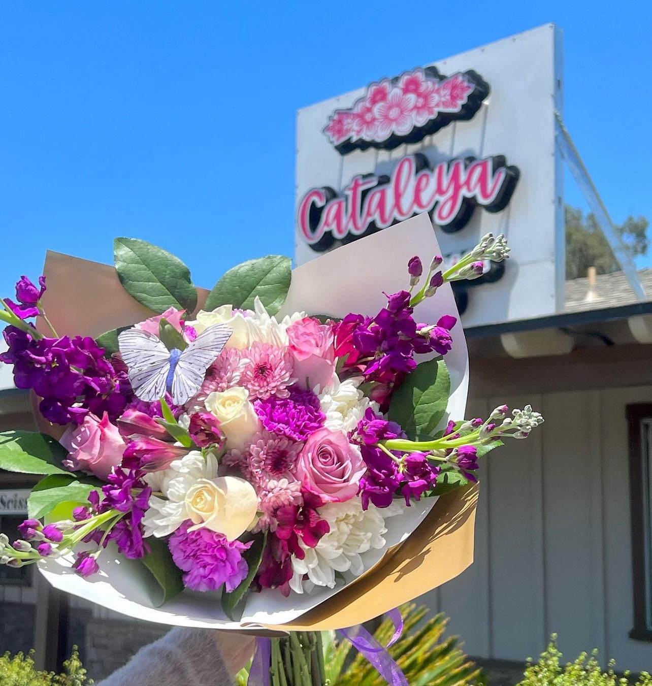 Bouquet of pink, white, and purple flowers with a butterfly decoration