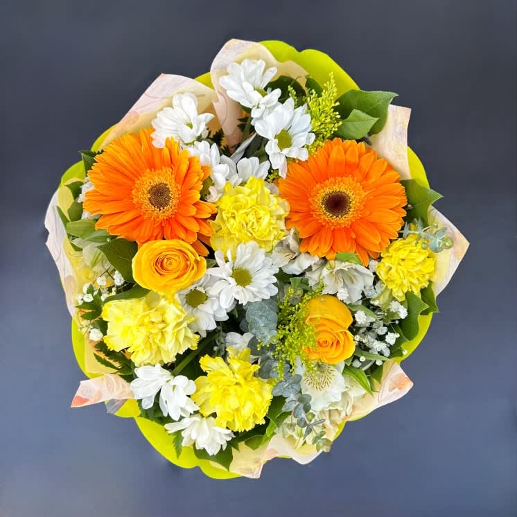 Bouquet of orange gerbera daisies, yellow roses, and white daisies