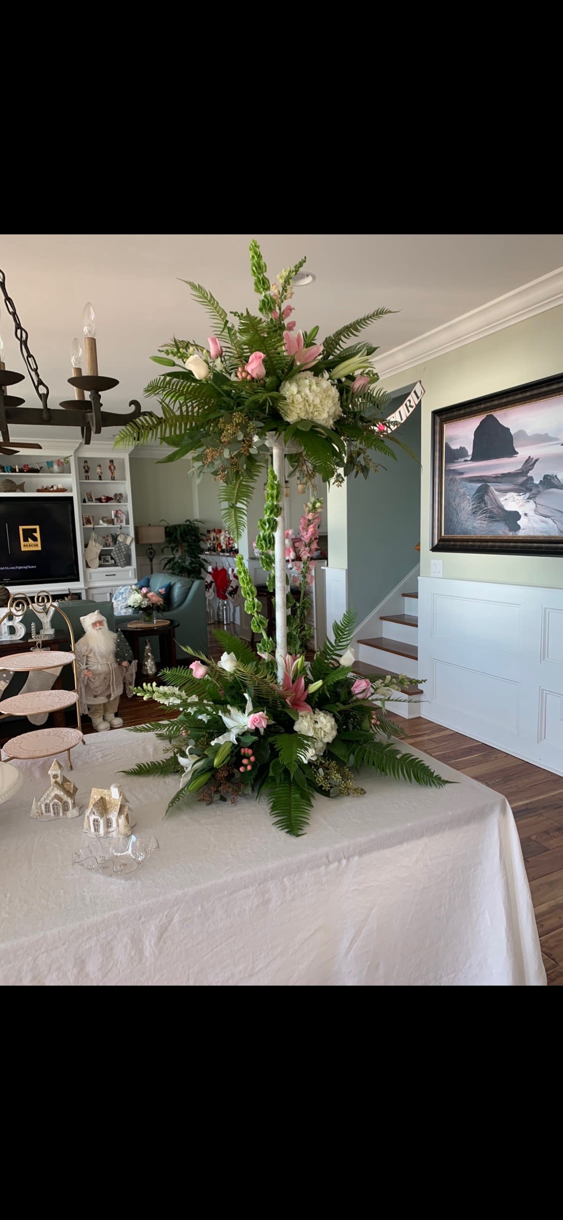 Tall floral centerpiece with pink and white blooms on a table