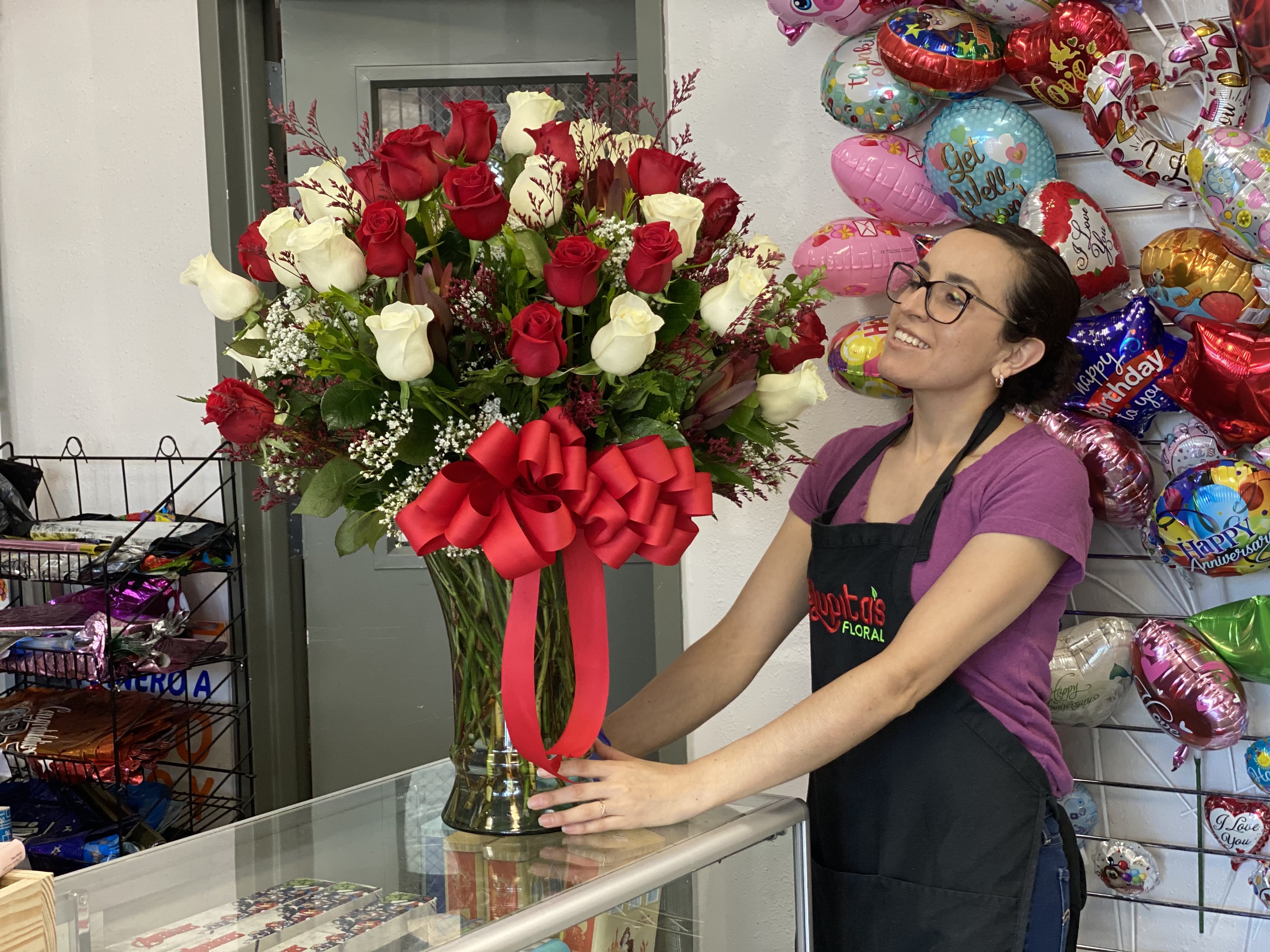 Tall bouquet of red and white roses in a glass vase with a red bow