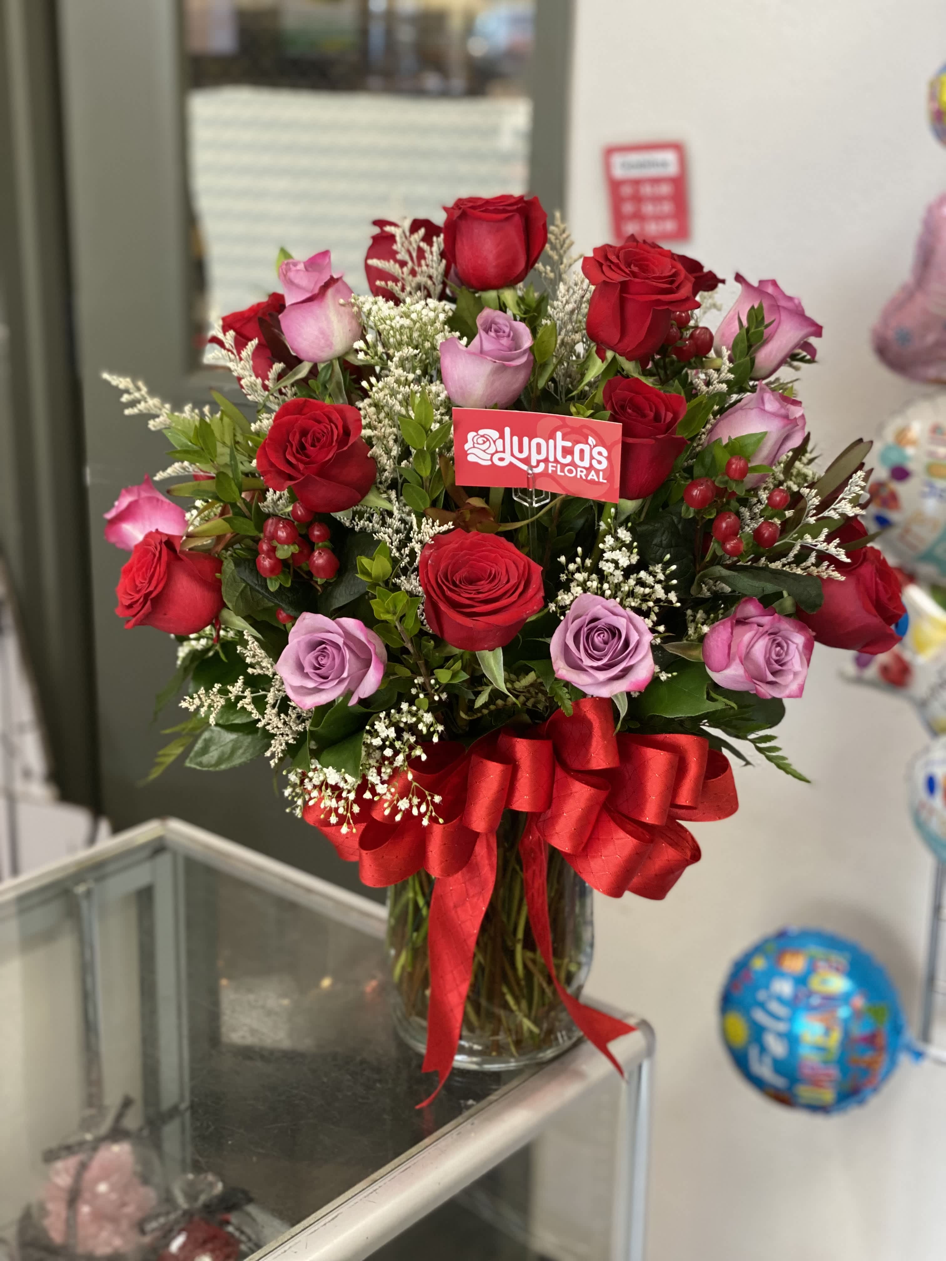 Bouquet of red and lavender roses in a glass vase with a red ribbon