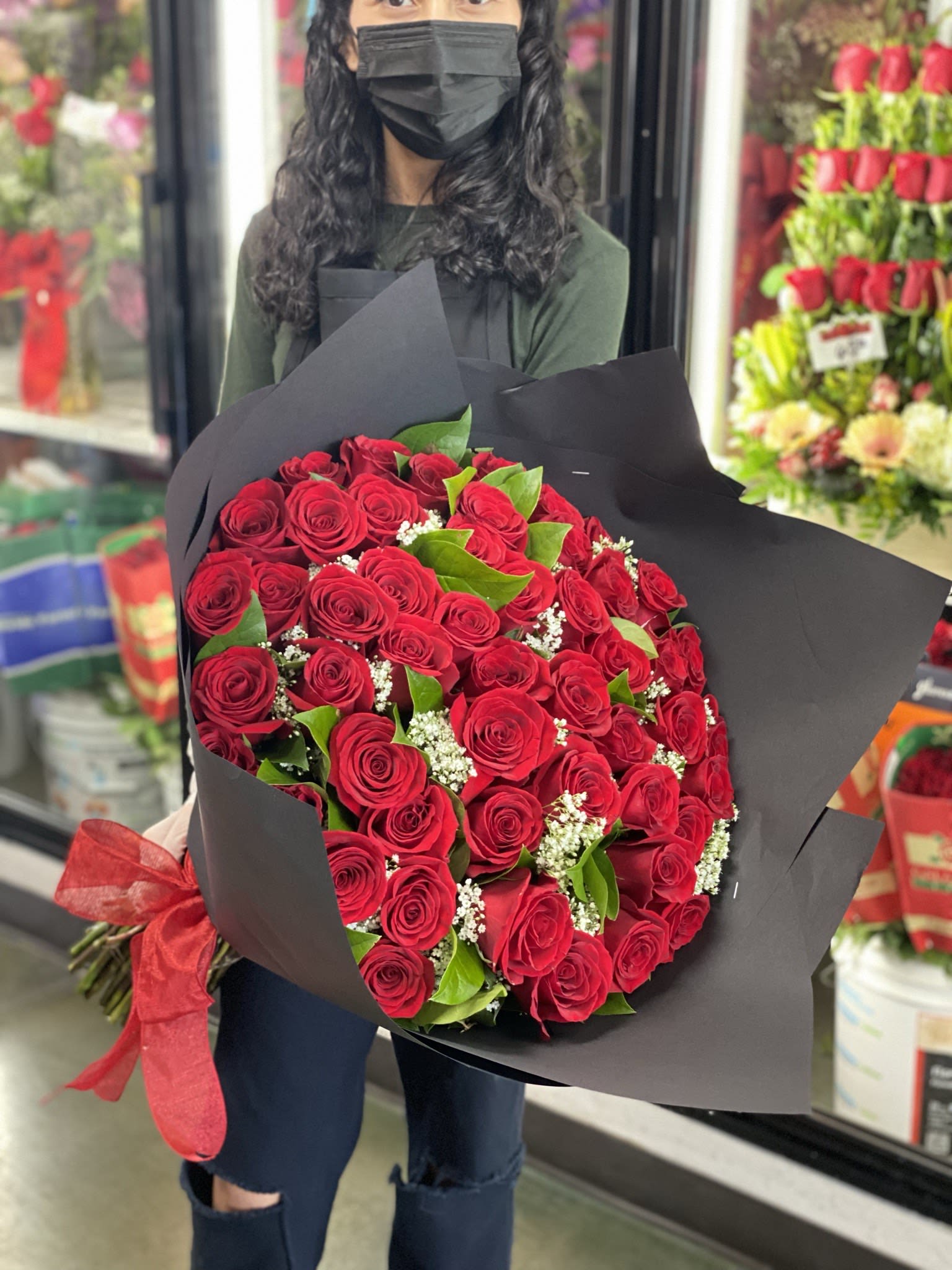 Large bouquet of red roses wrapped in black paper with a red ribbon