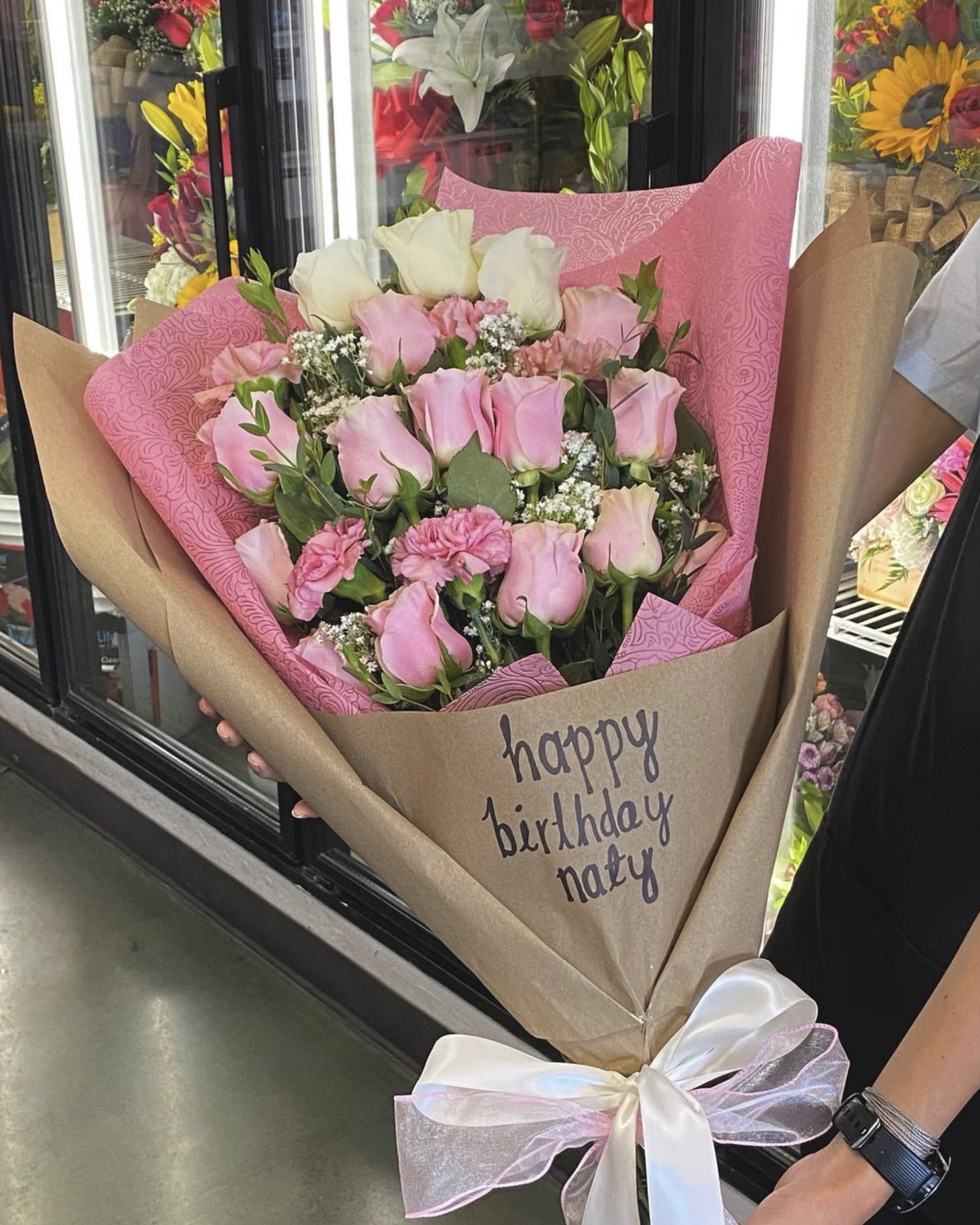 Pink and white rose bouquet wrapped in brown paper with a ribbon