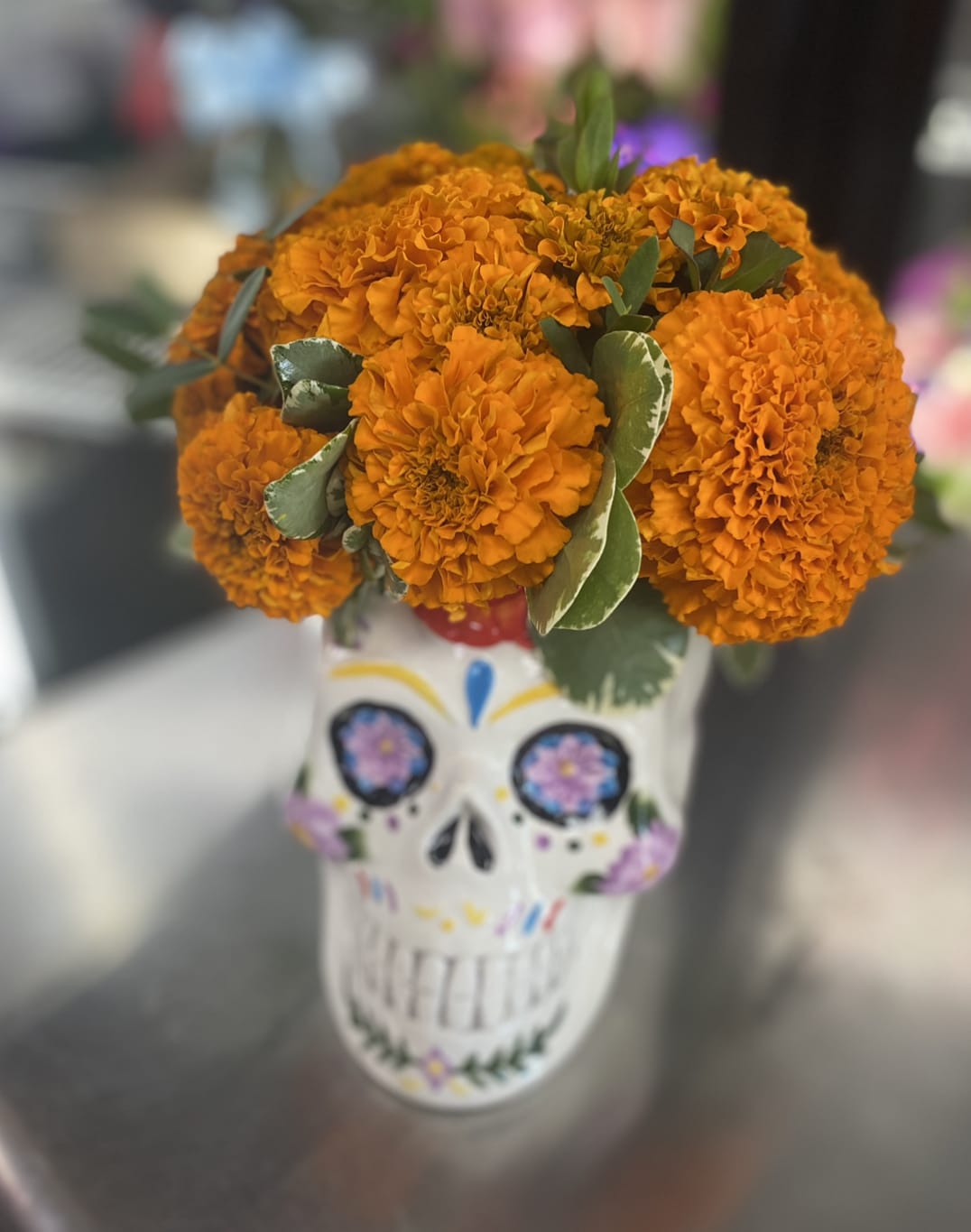 Orange marigold bouquet in a painted skull vase