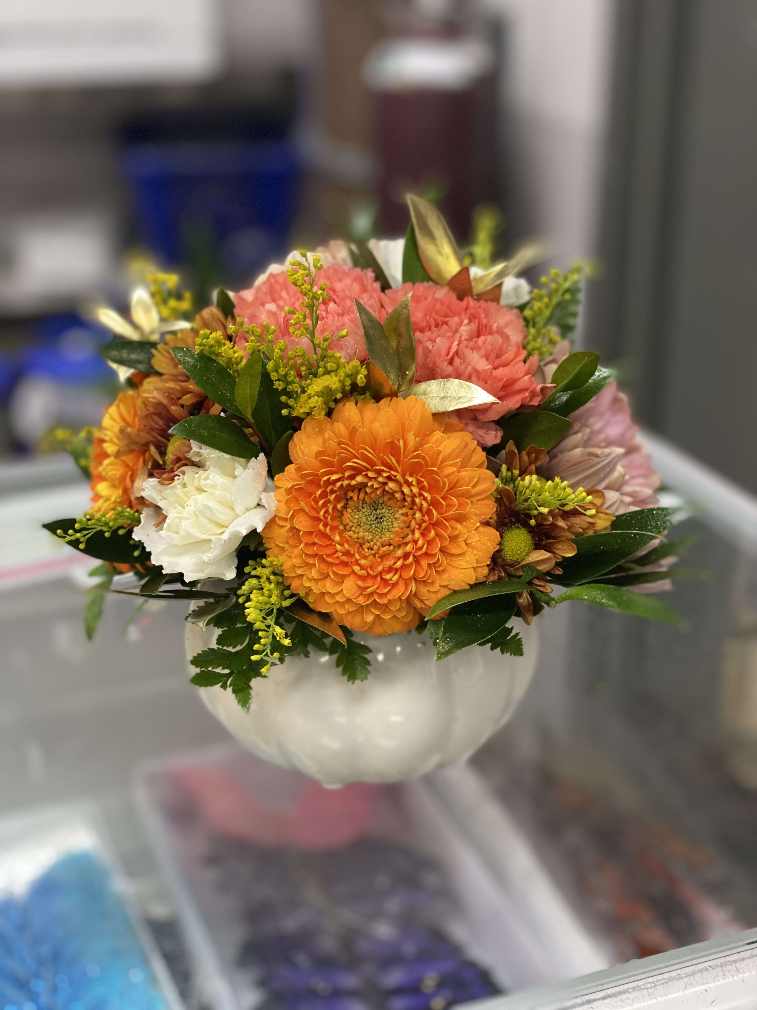 Mixed orange, pink, and white flowers arranged in a white vase